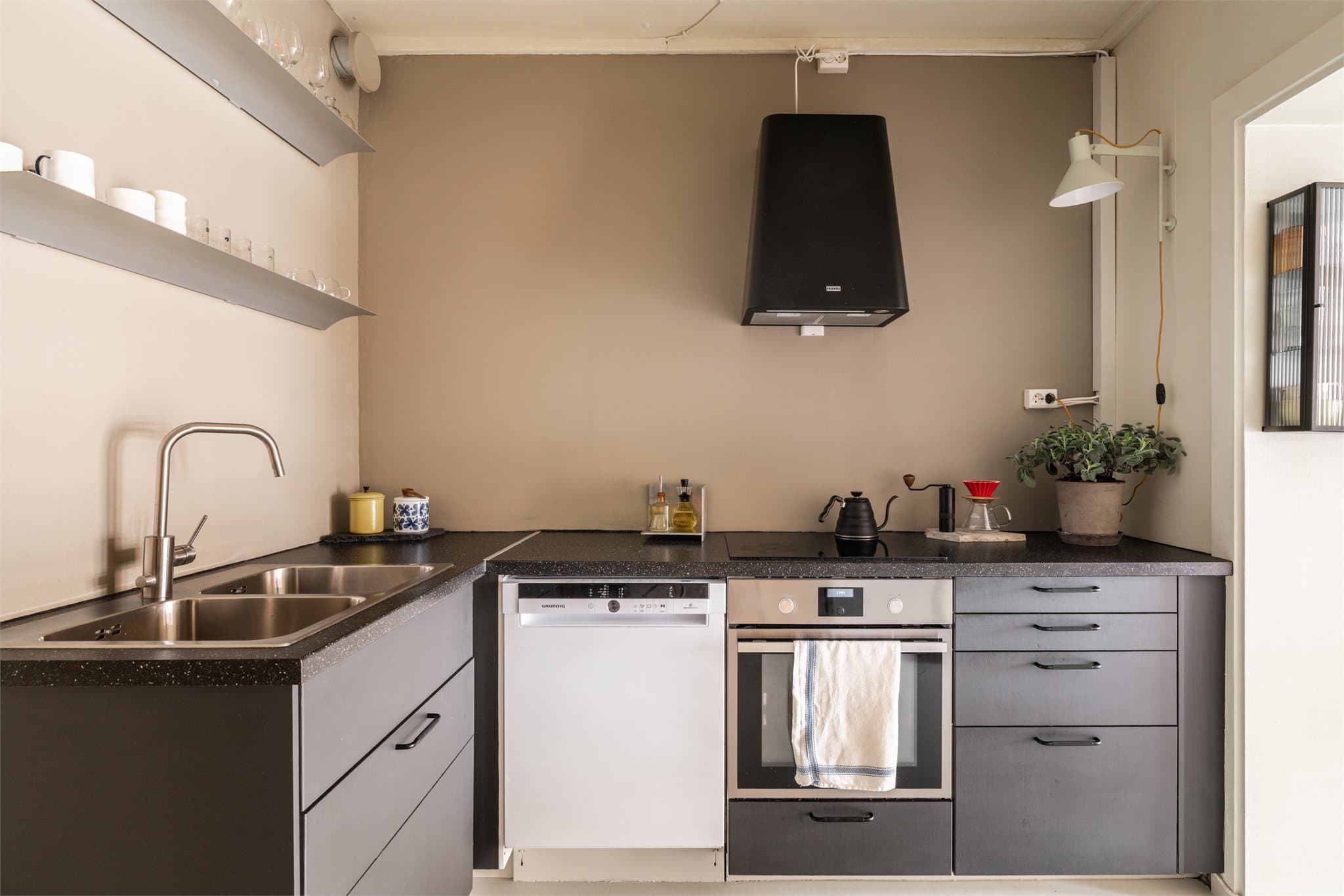 Innredningen fremstår som eldre, men godt ivaretatt og funksjonell – med glatte fronter, laminatbenkeplate og planlimt kum i rustfritt stål.