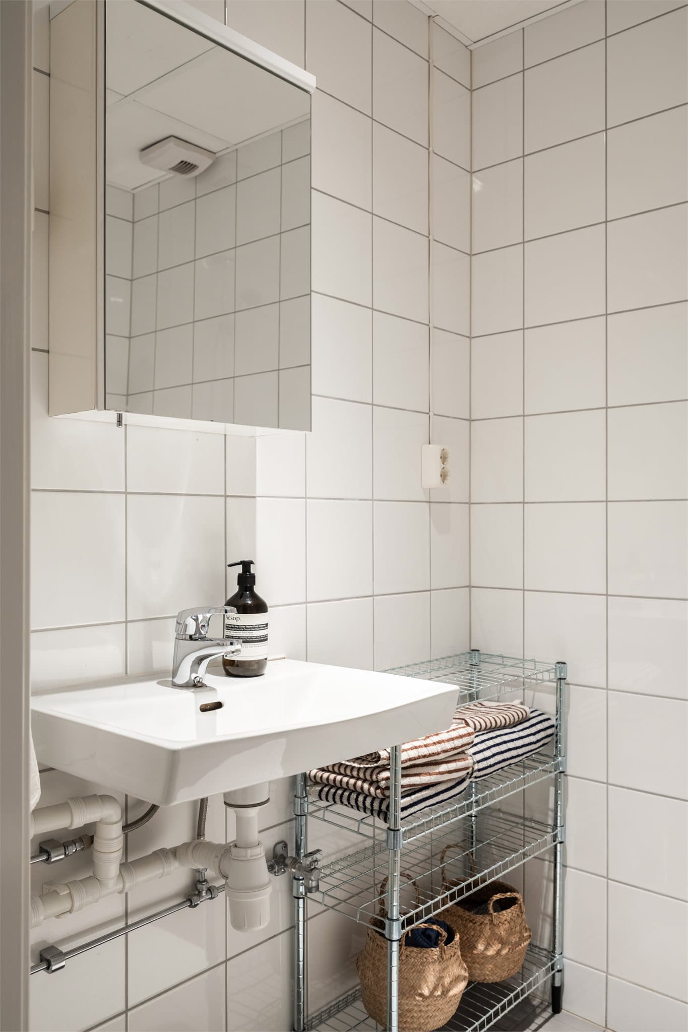 Innredningen består av servant med speilskap, vegghengt toalett og dusjhjørne med termostatstyrt blandebatteri.