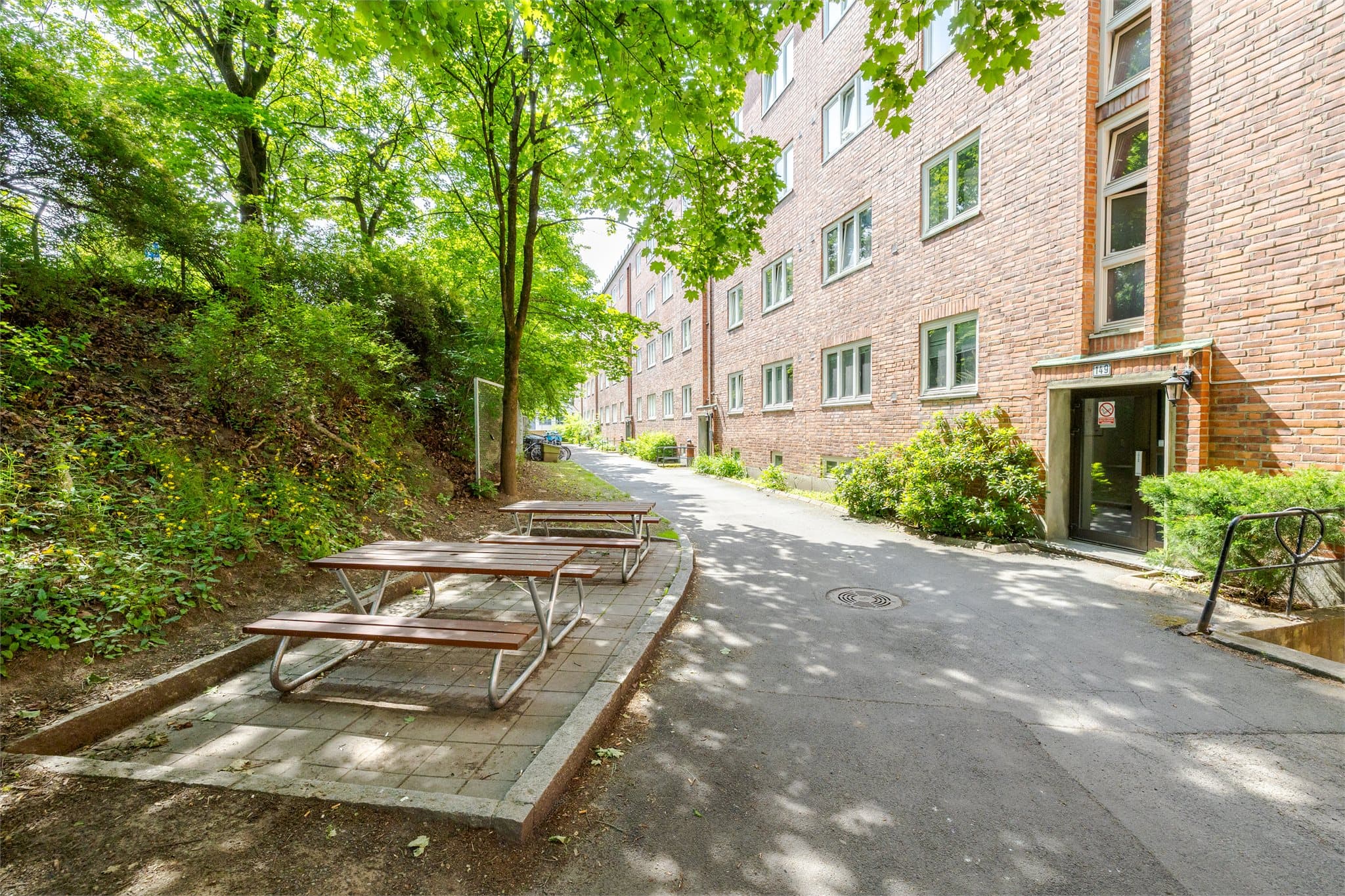 Baksiden av bygget er velholdt med trær og sittegrupper.