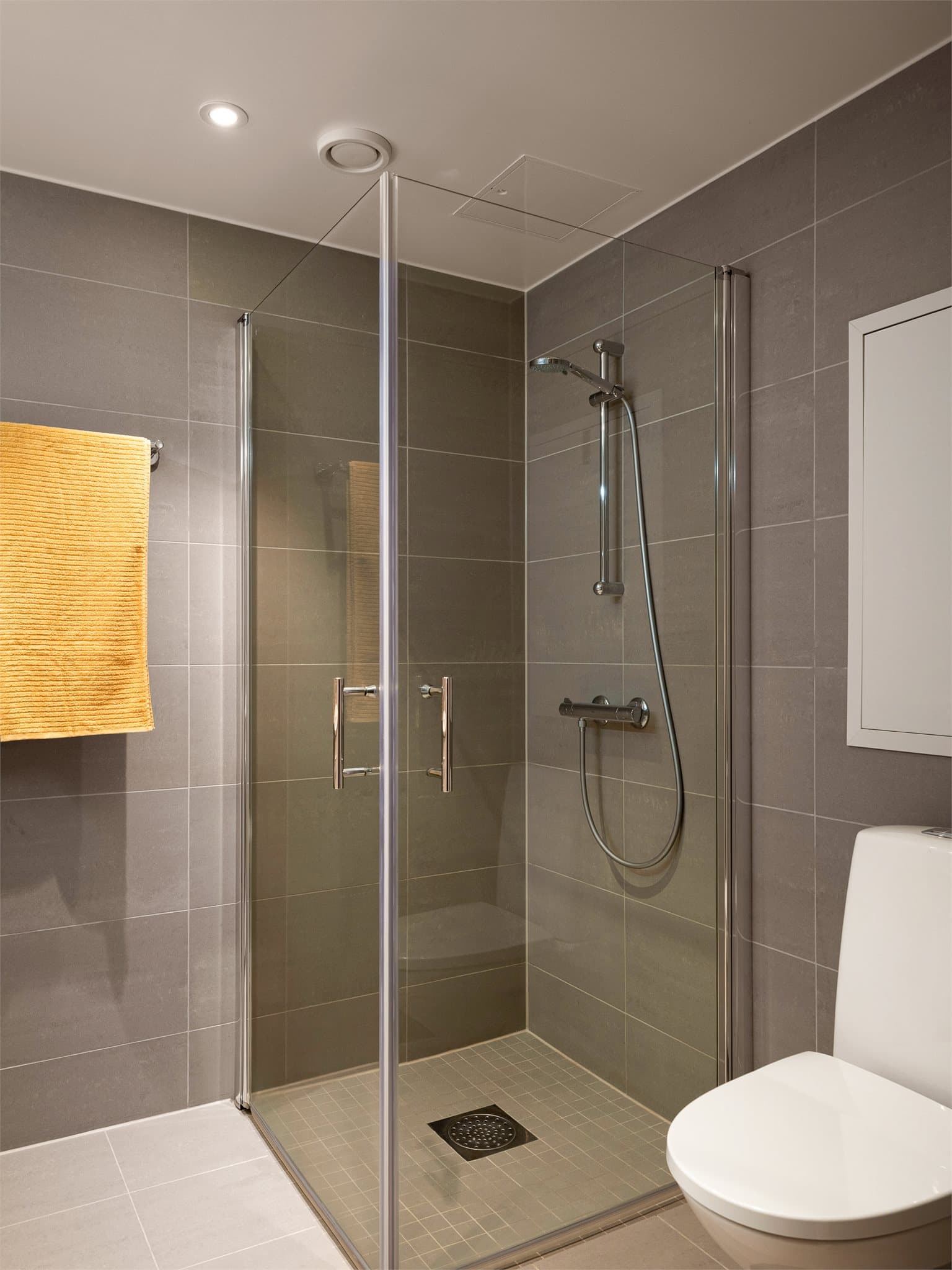 Dusjhjørne med svingbare glassdører og innfelte downlights i himlingen for god belysning.