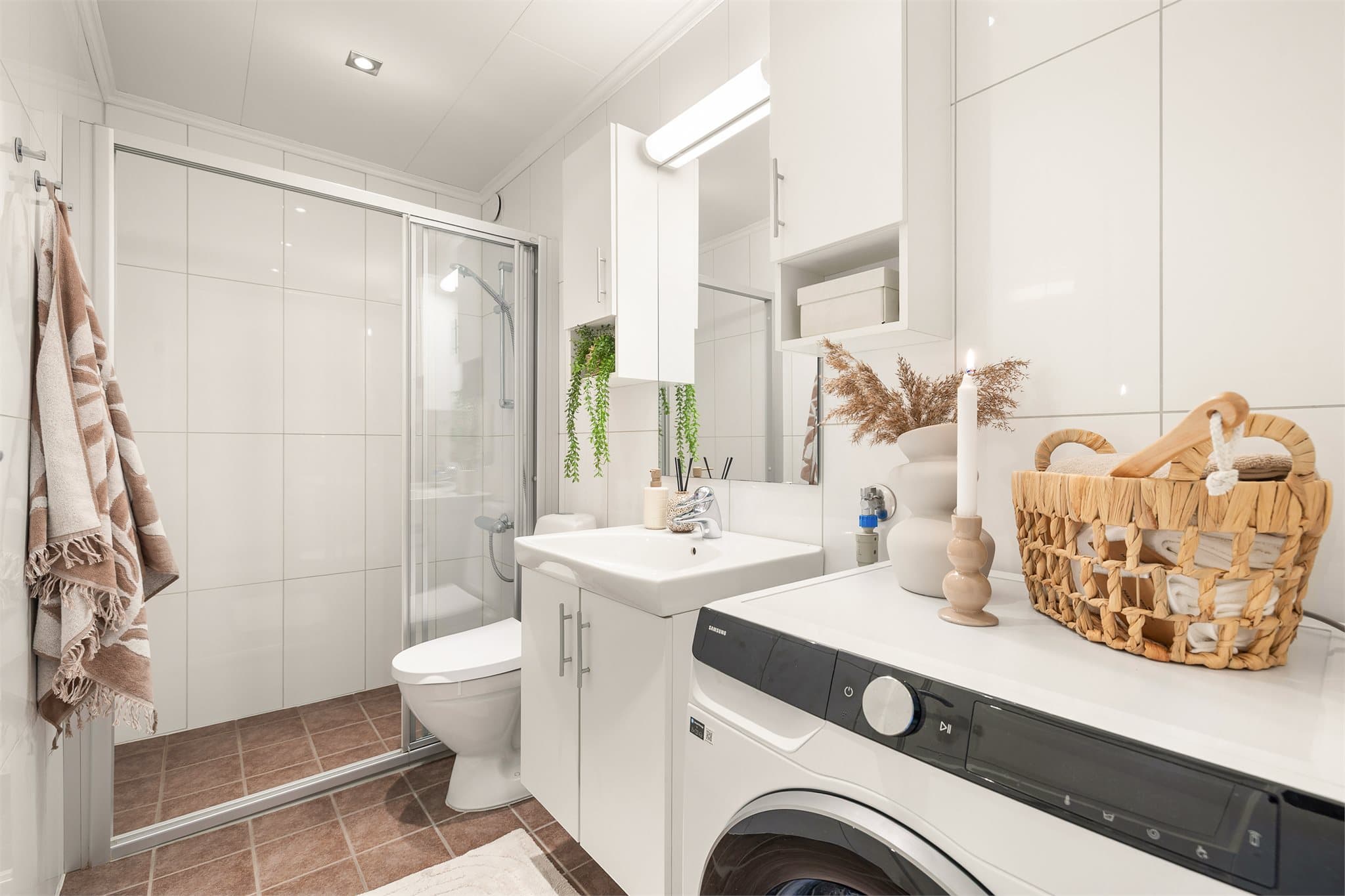 Badet er utstyrt med servantinnredning, speilskap, skap, dusjnisje med glassdører samt opplegg for vaskemaskin.