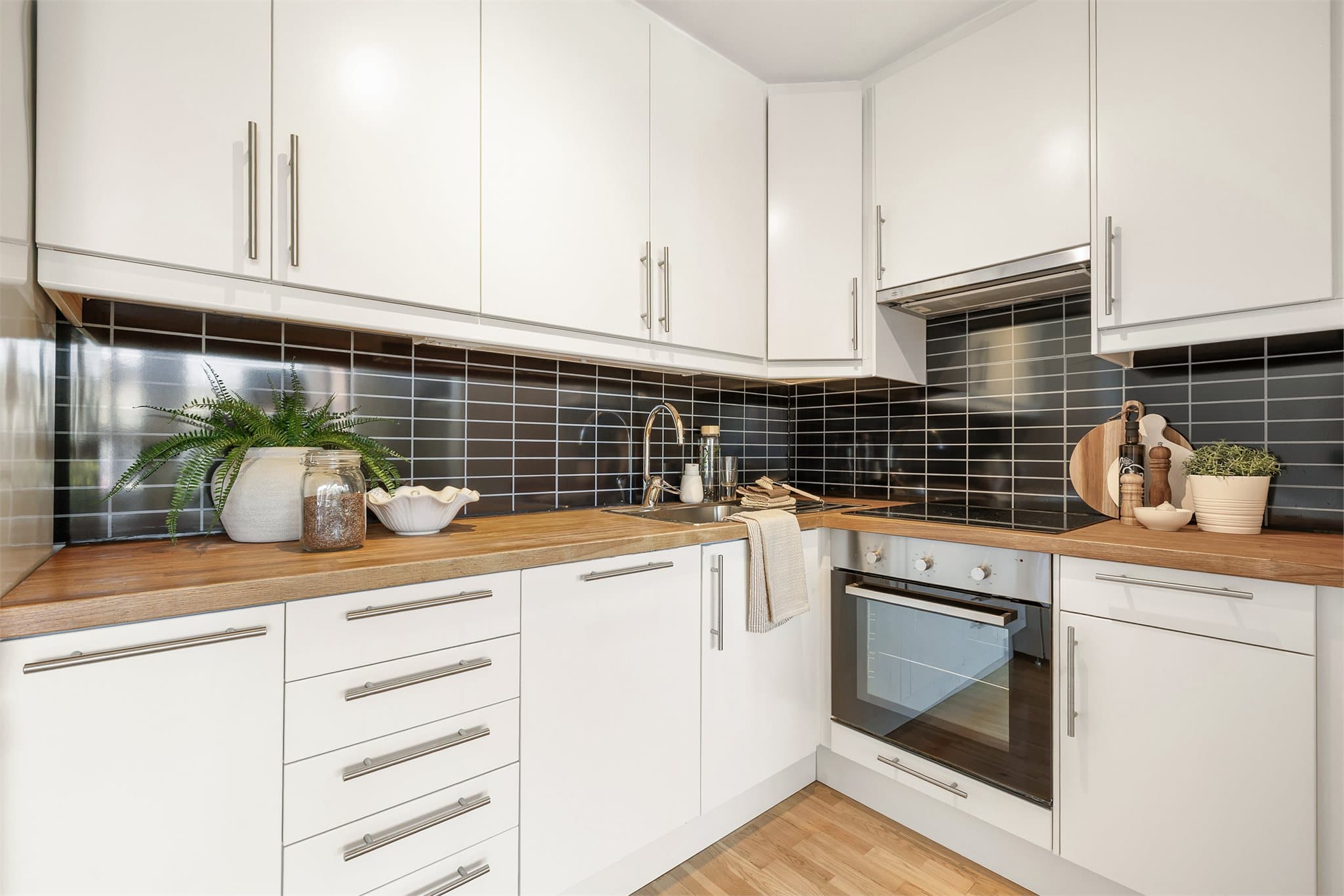 Lyst kjøkken med glatte fronter, rikelig skap- og benkeplass, samt overskap som går helt opp til himlingen.