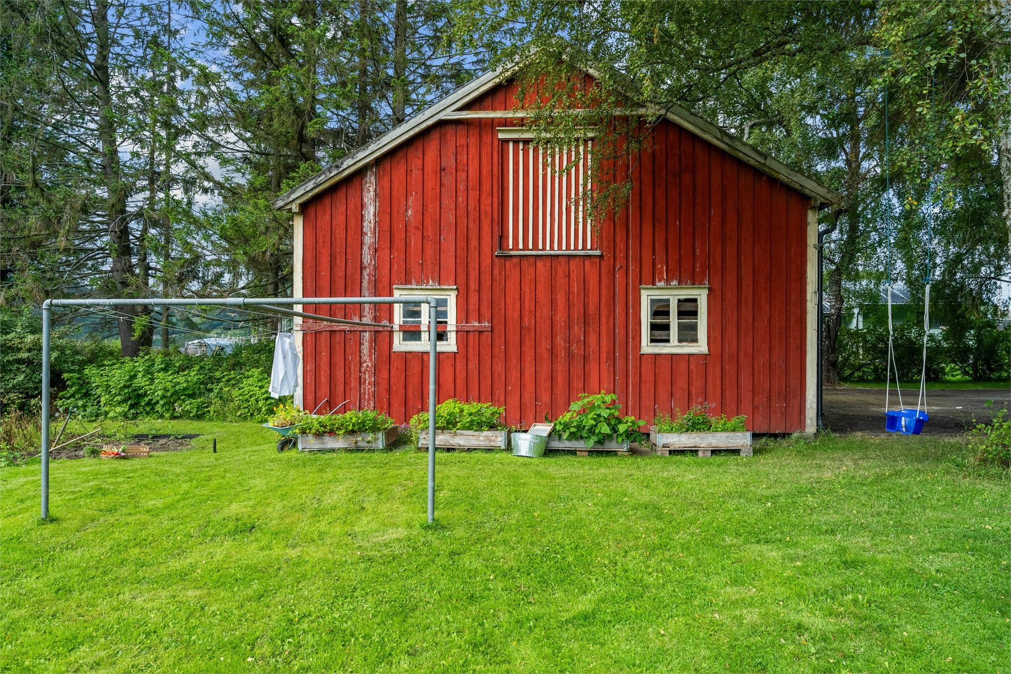 Uteområdet har flere praktiske kvaliteter, med uthus, tørkestativ og god plass rundt bygningene.