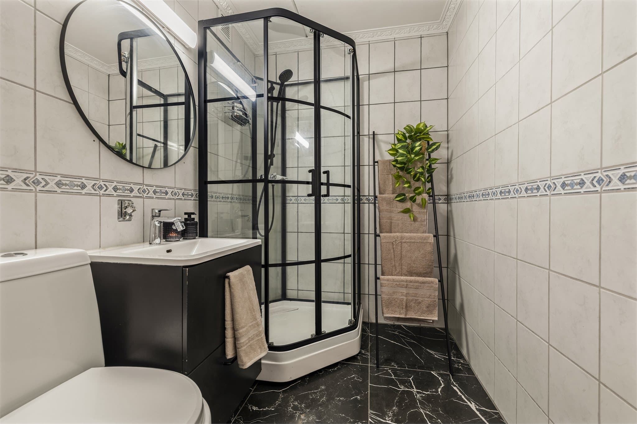 Helfliset baderom innredet med servant, gulvstående klosett og dusjkabinett.