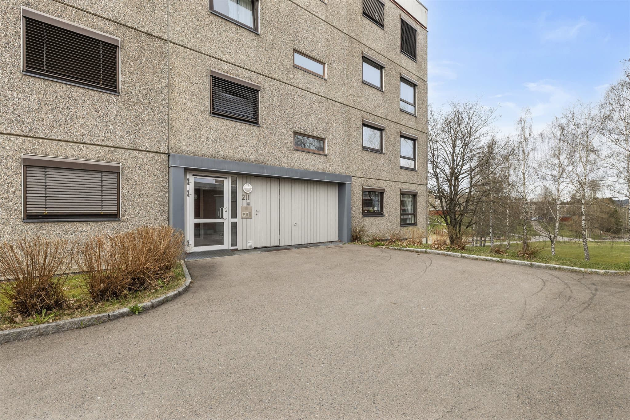 Fasade med inngangsparti og en praktisk utebod rett utenfor.