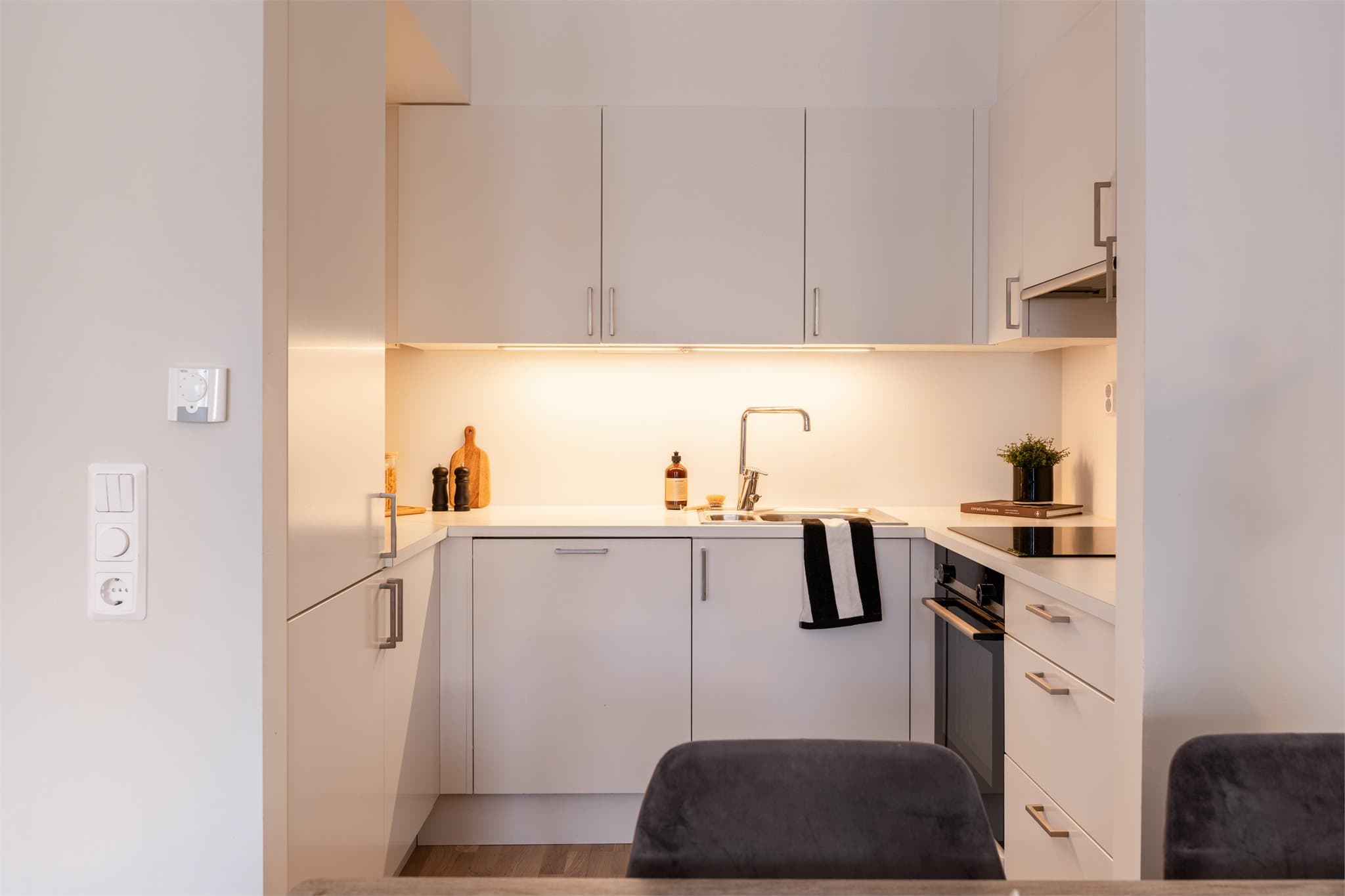 Kjøkkenet fra Sigdal har en stilren innredning med glatte, hvite fronter og laminat benkeplate.