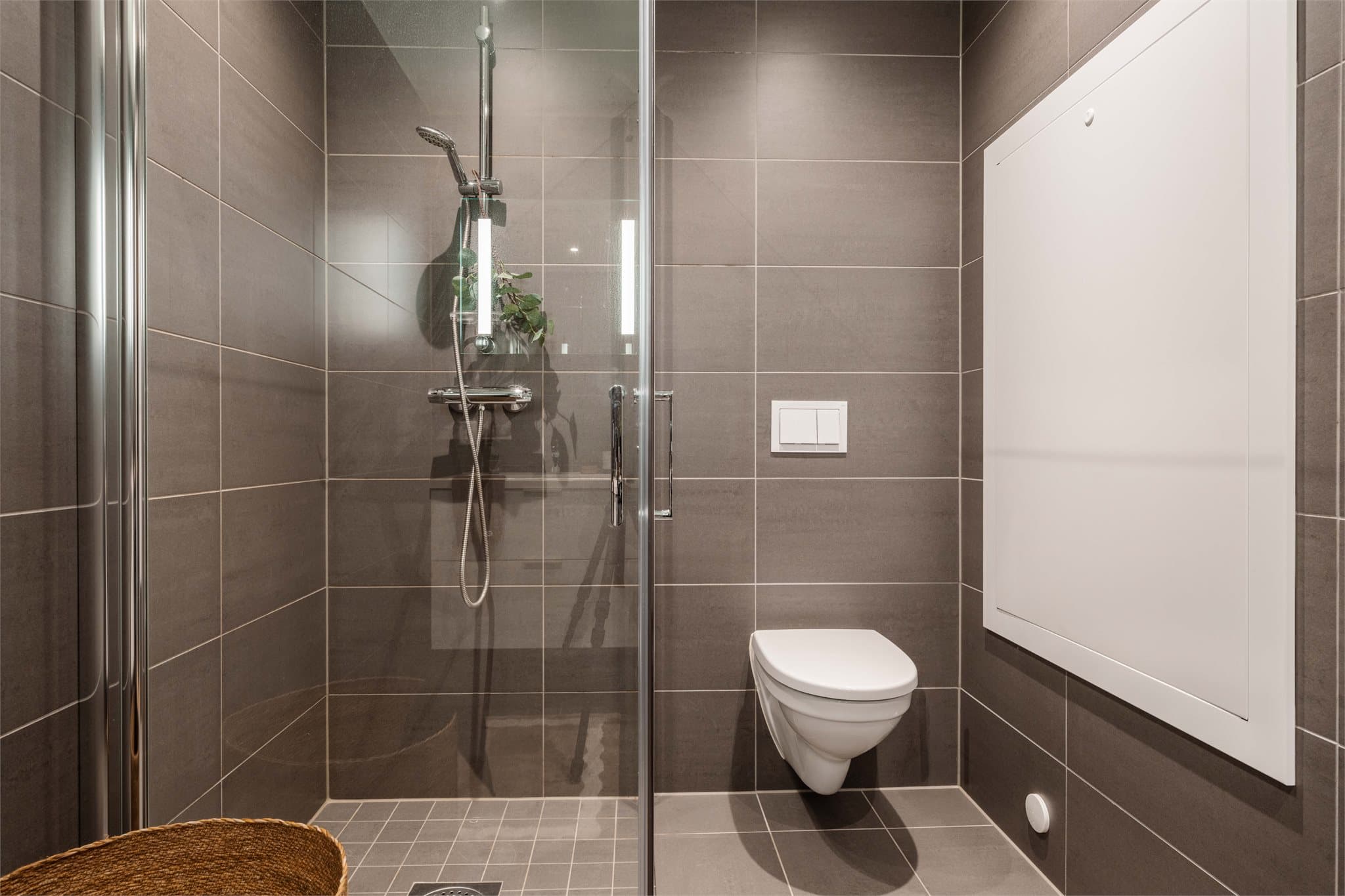 Badet er utstyrt med vegghengt toalett og innfellbare dusjvegger med nedsenket gulv i dusjsonen.