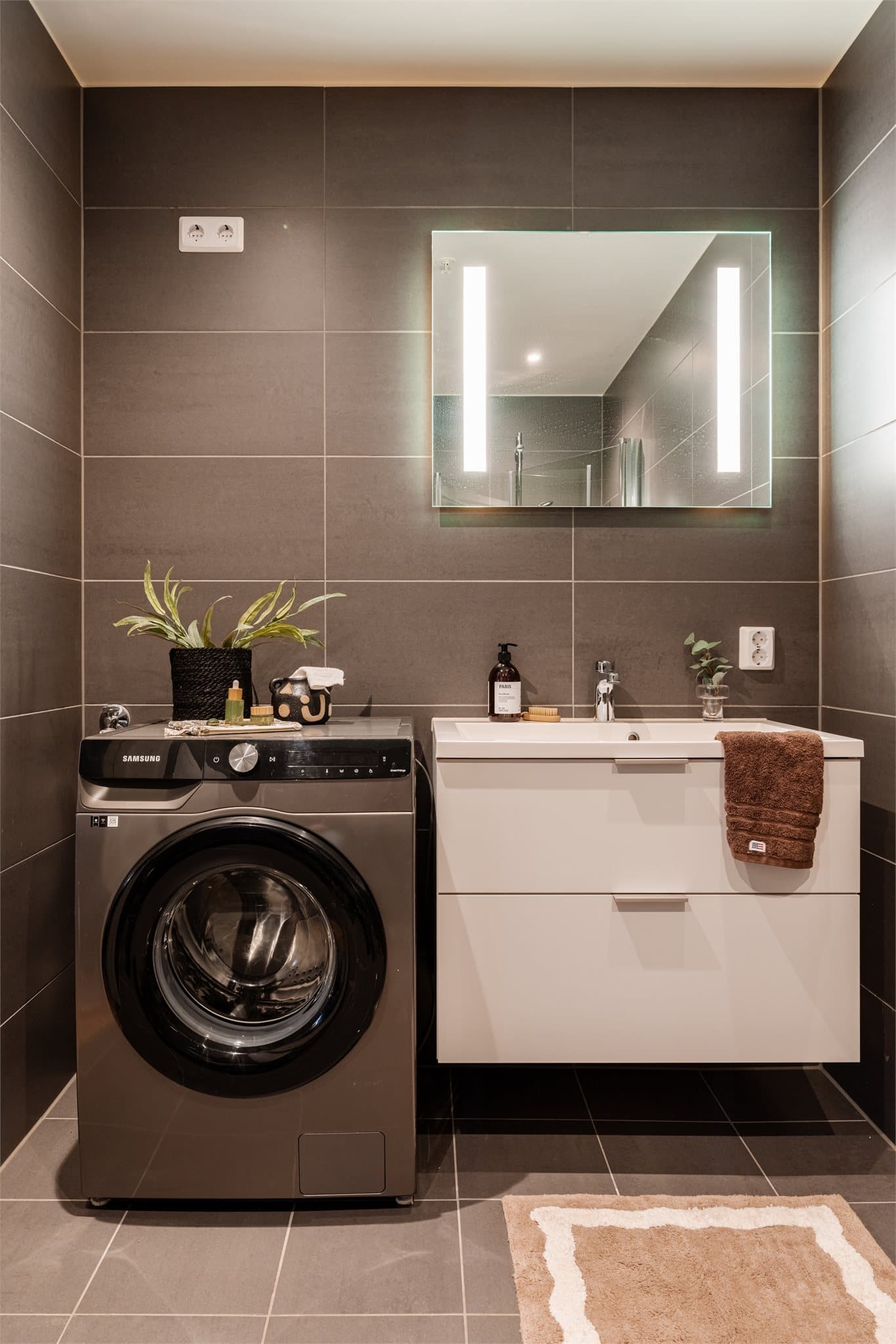 Servantskap, speil med belysning og opplegg for vaskemaskin gjør badet komplett.