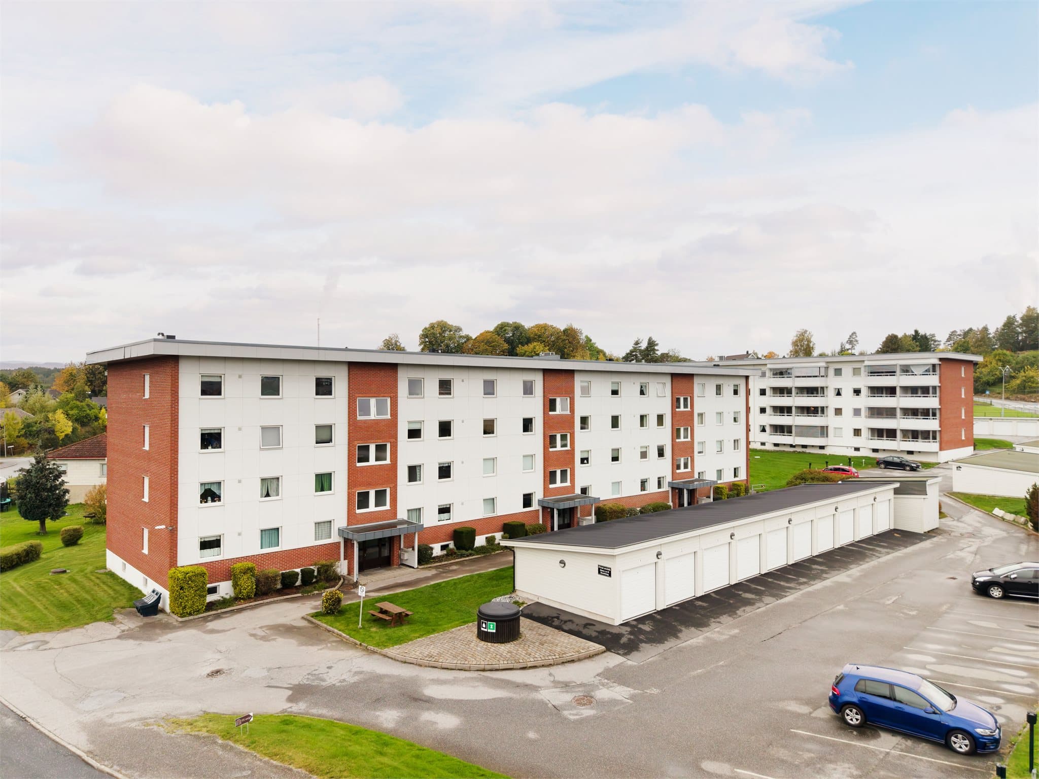 Fellesområde med asfalterte parkeringsarealer og kildesortering i garasjerekken.
