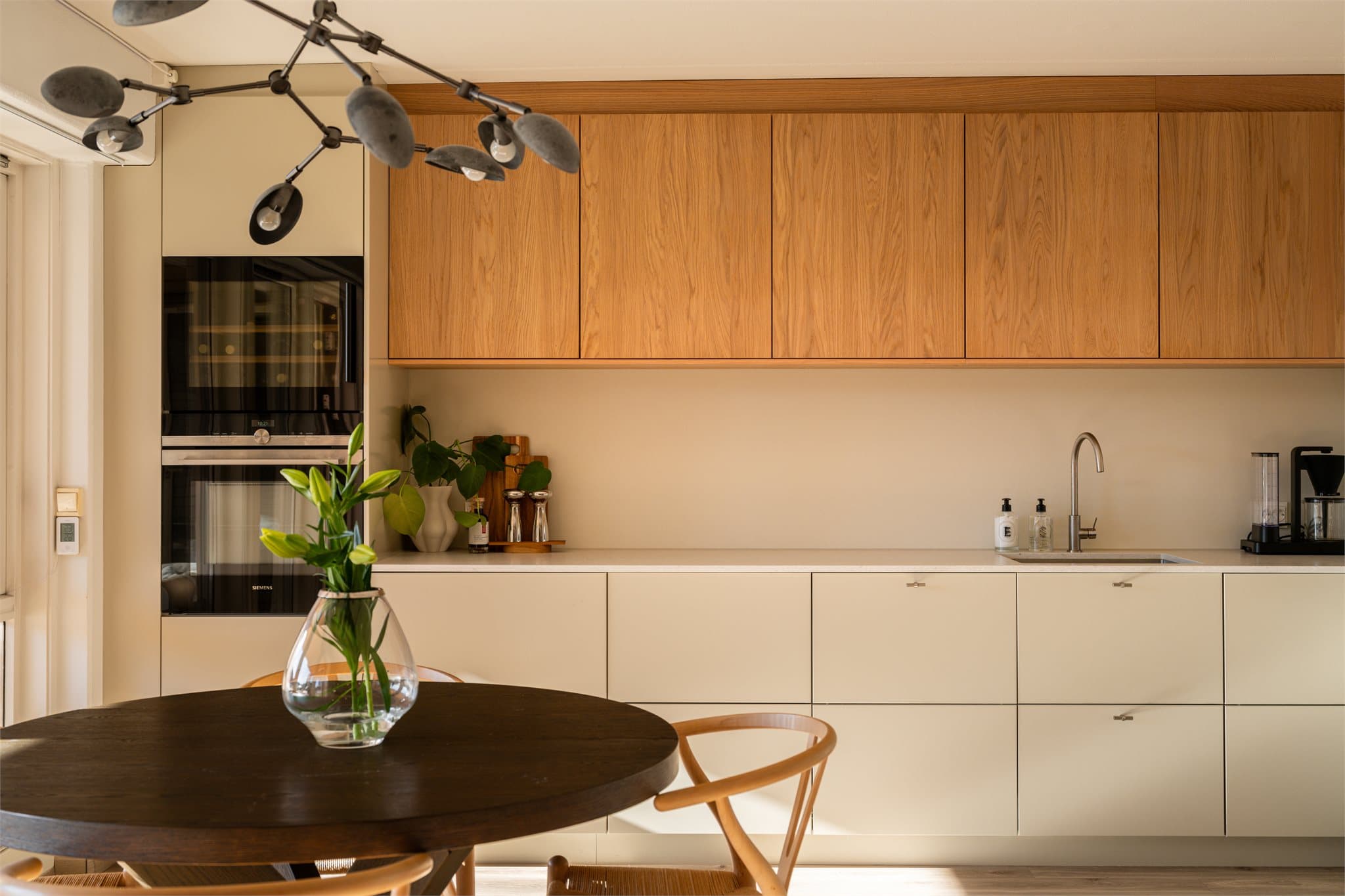 Innredningen har et stilrent og eksklusivt uttrykk med glatte, moderne fronter, elegante overskap i eik og en lekker benkeplate i steinkompositt.
