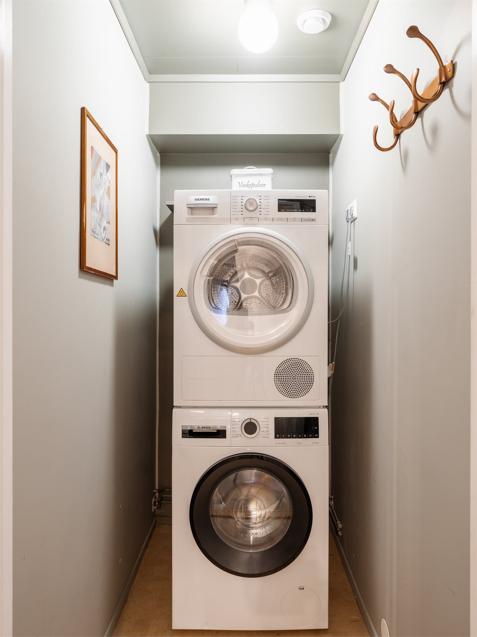 Et separat rom er innredet som praktisk vaskerom med opplegg for vaskesøyle.