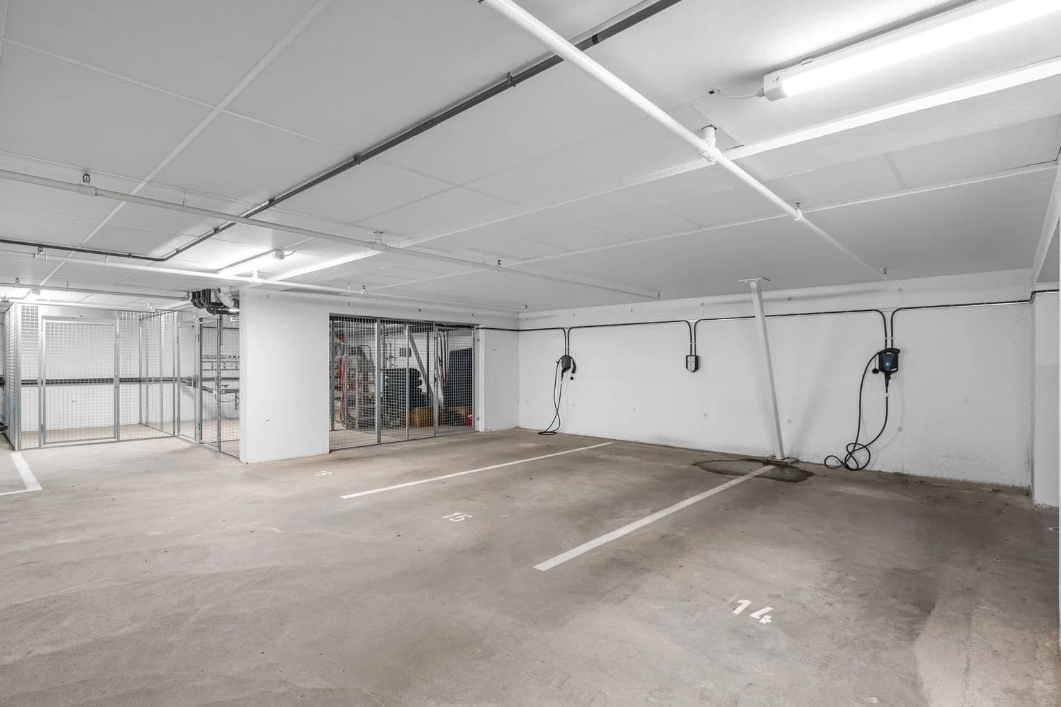 Det disponeres egen parkeringsplass med lademulighet (må bestilles via sameiet) i felles garasjekjeller. Bilde er av en annen parkeringsplass i sameiet