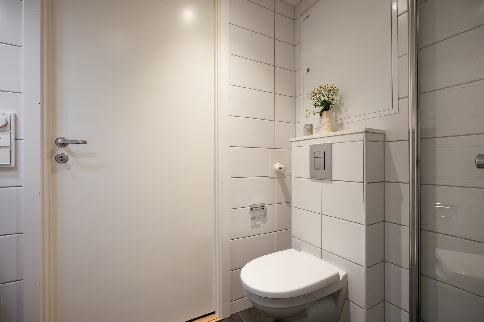 Vegghengt toalett, nedsenket dusjnisje og innfellbare dusjdører.