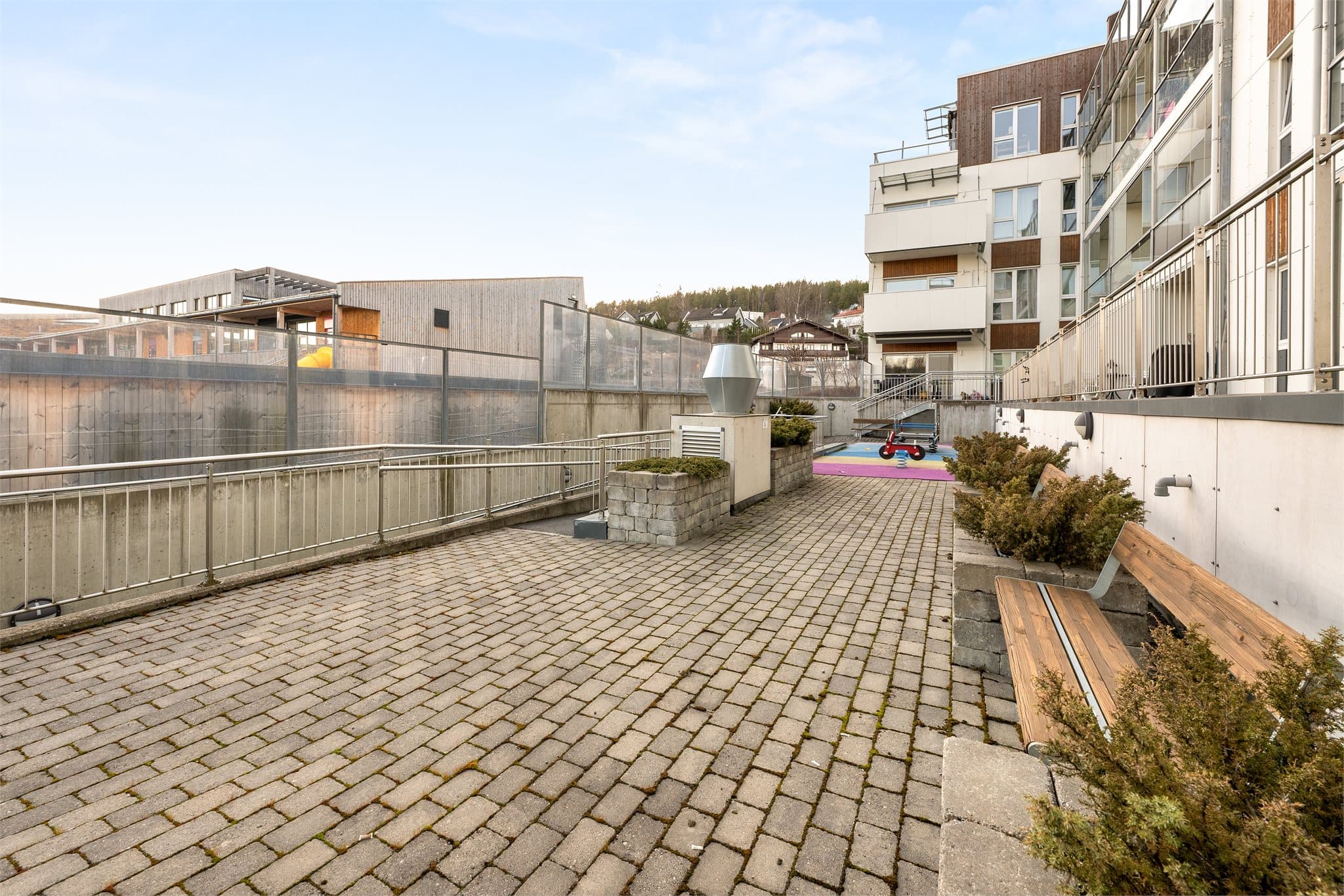 Fellestomten er pent opparbeidet med steinbelagte områder, frodige prydbusker og stemningsfull utebelysning. Det er lekestativer og sittebenker til felles anvendelse i bakgården.