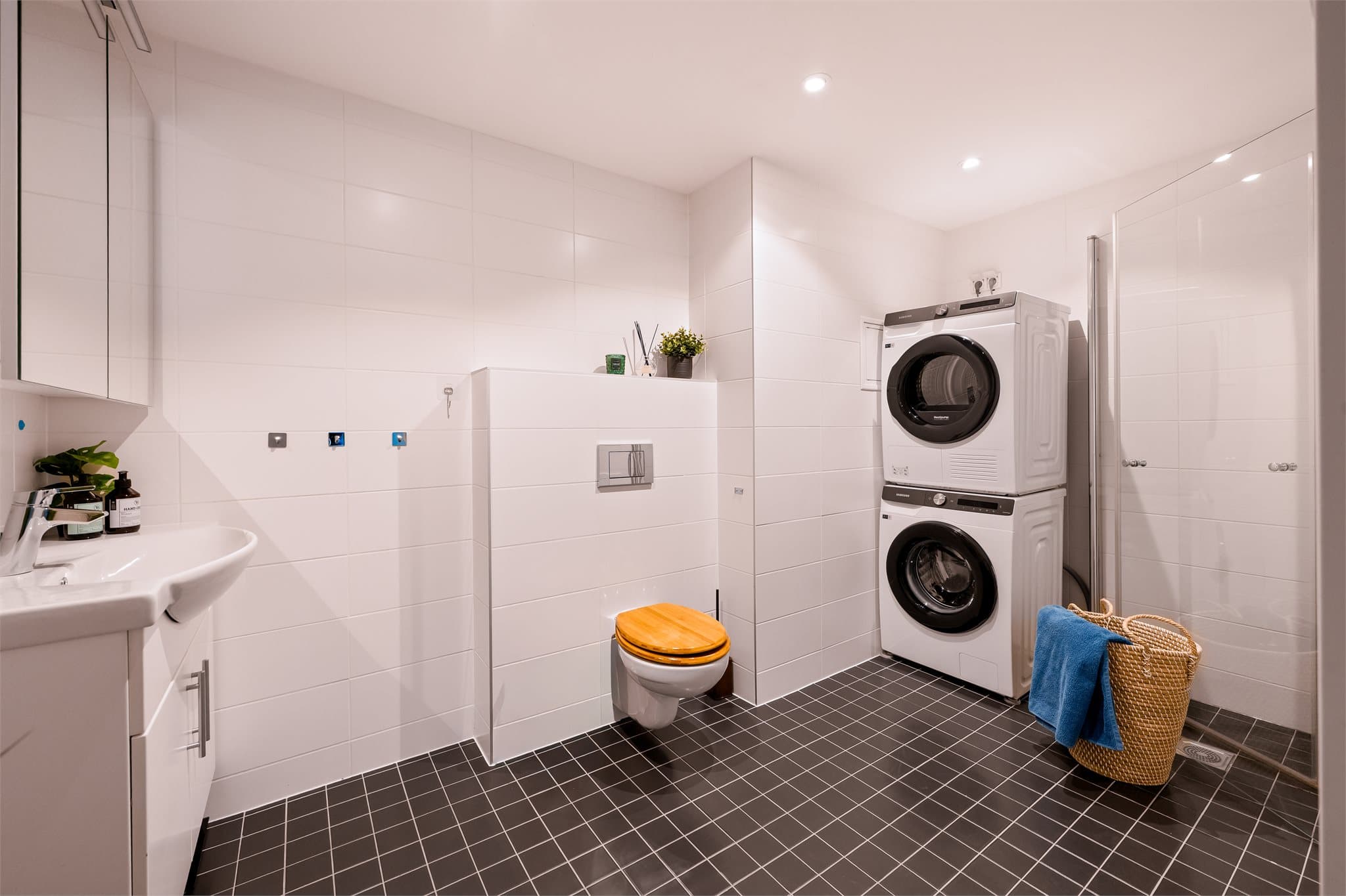 Badet er innredet med servant, vegghengt toalett, dusjhjørne samt opplegg for vaskemaskin og tørketrommel.