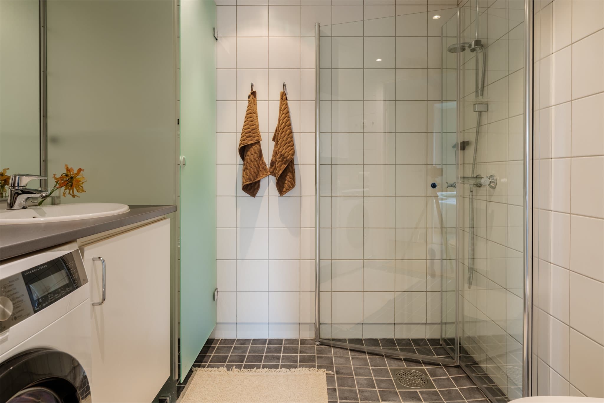 Badet har flislagte vegger, flislagt gulv med elektriske varmekabler og panelplater i tak med downlights.