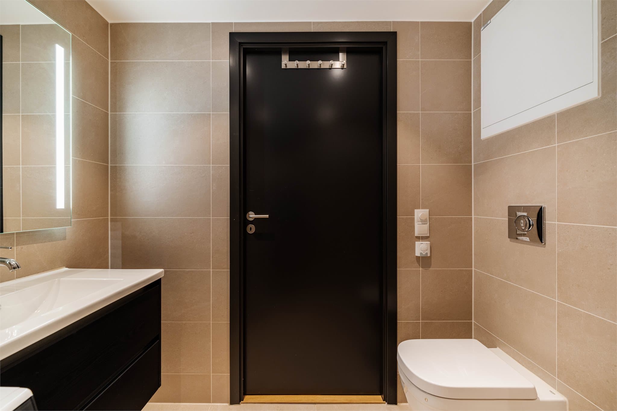 Badet er innredet med vegghengt toalett med innebygd sisterne, servantinnredning og speil med belysning.