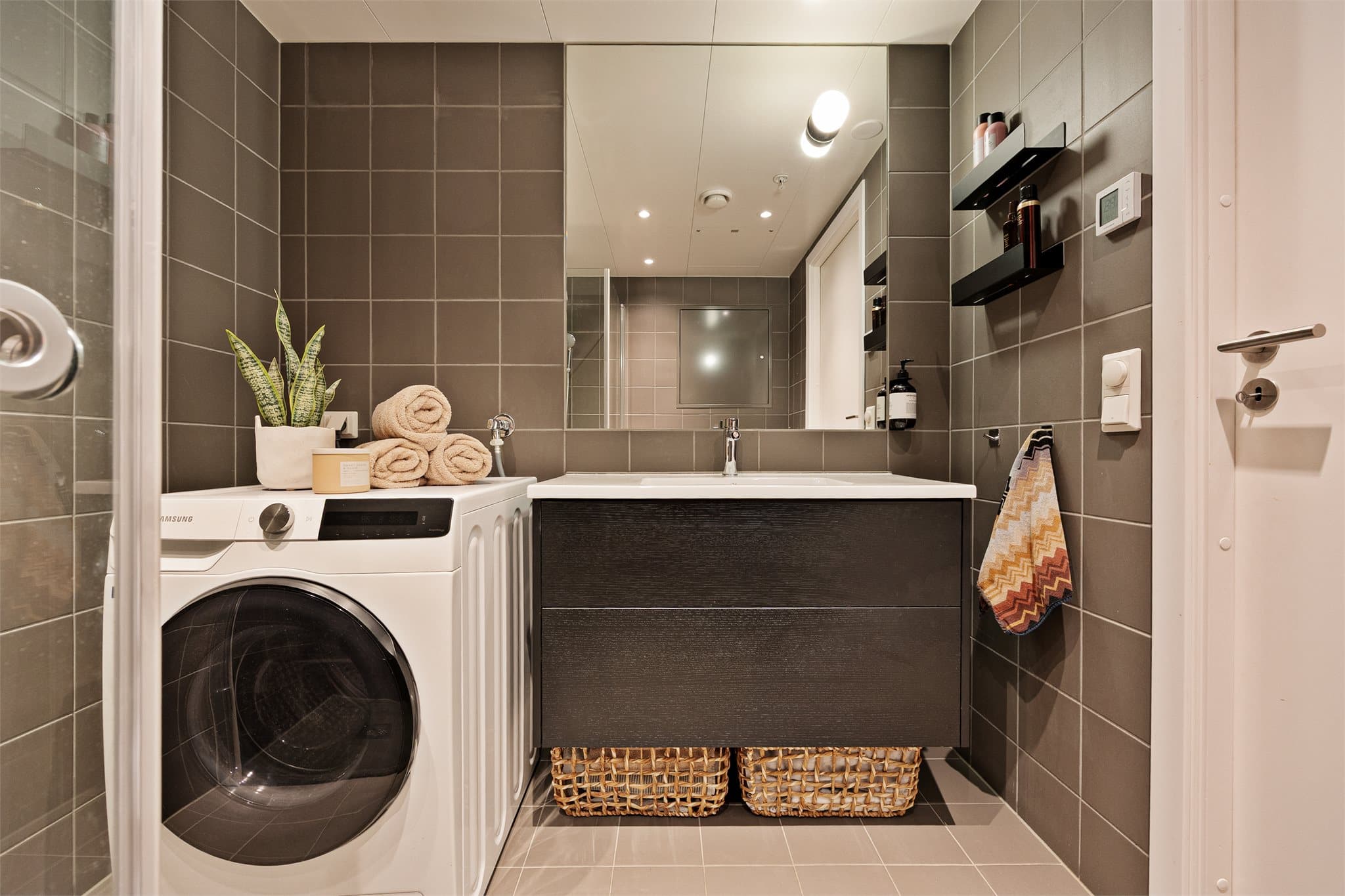 Innredningen består av helservant på vegghengt skuffeseksjon, vegghengt toalett og dusjhjørne med innfelle dusjdører. Opplegg for vaskemaskin.