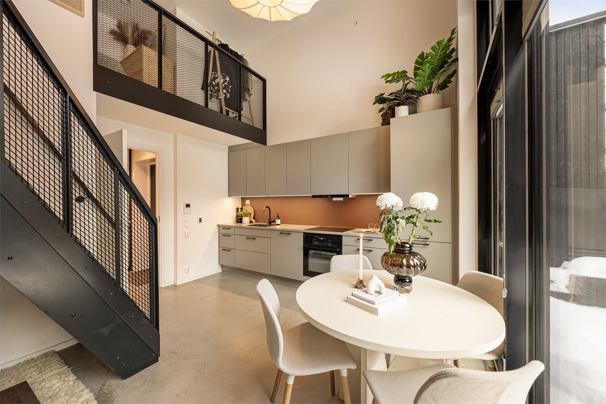 For øvrig er oppholdsrommet malt i tidsriktige fargetoner som komplimentert med et lekkert, slipt betonggulv.