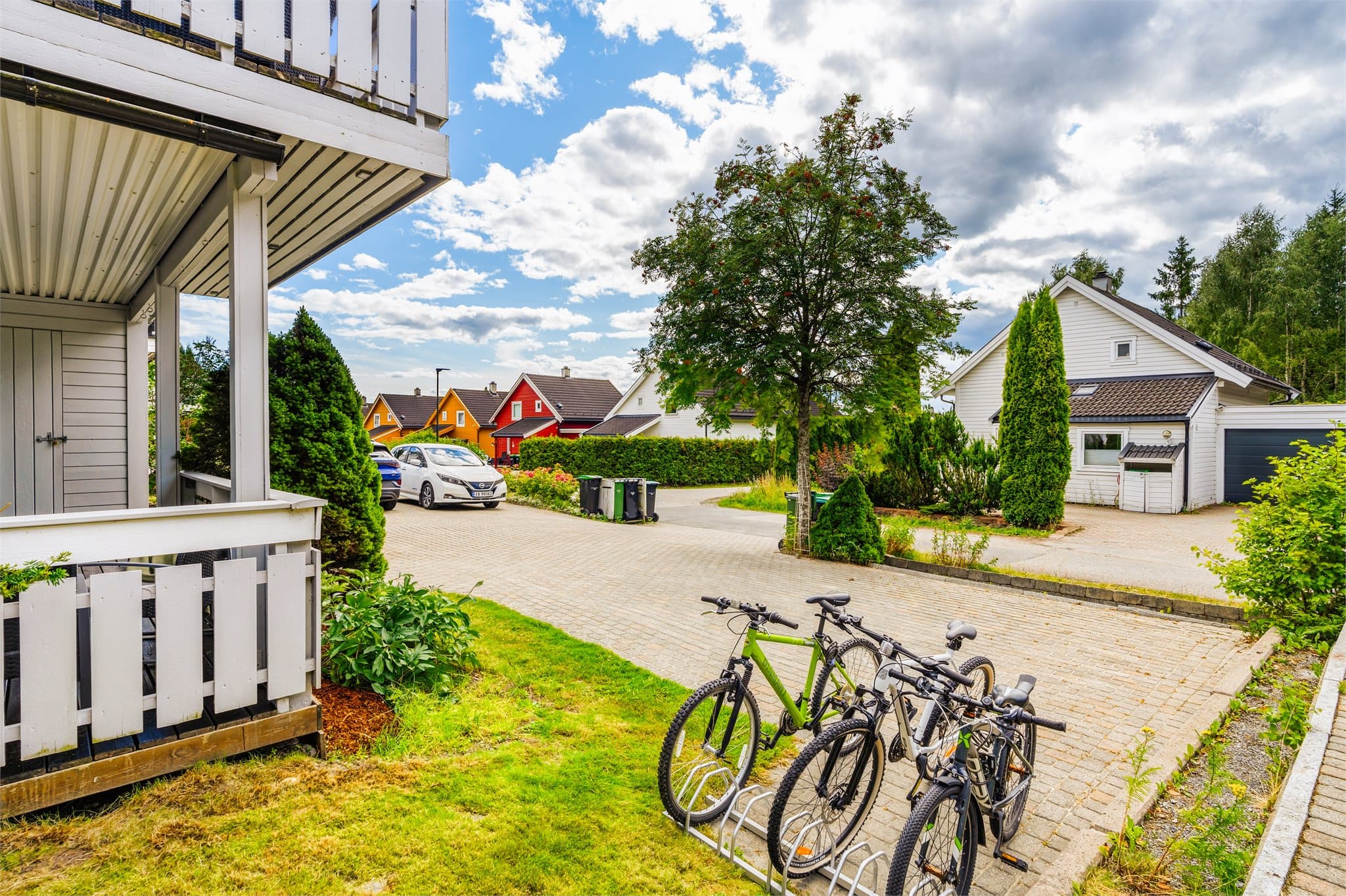 Godt med parkeringsplass på steinbelagt gårdsplass. Det er installert elbil-lader på veggen ved inngangspartiet.