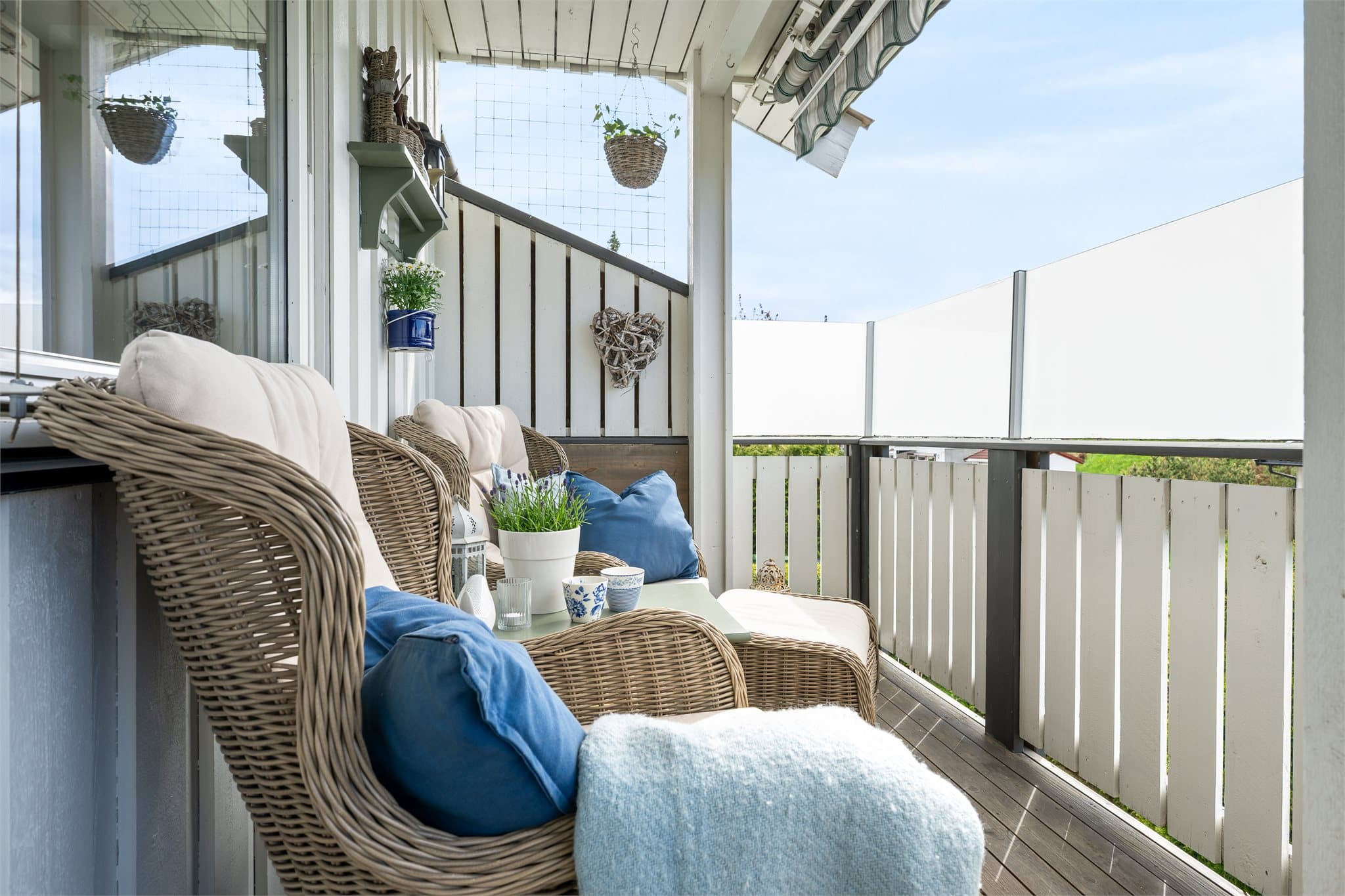 De lyse fasadene og det grønne utsynet gir en rolig og innbydende ramme rundt uteplassen, mens glasskjermingen bidrar til både ly og et moderne uttrykk. En perfekt forlengelse av boligen i den varme årstiden.