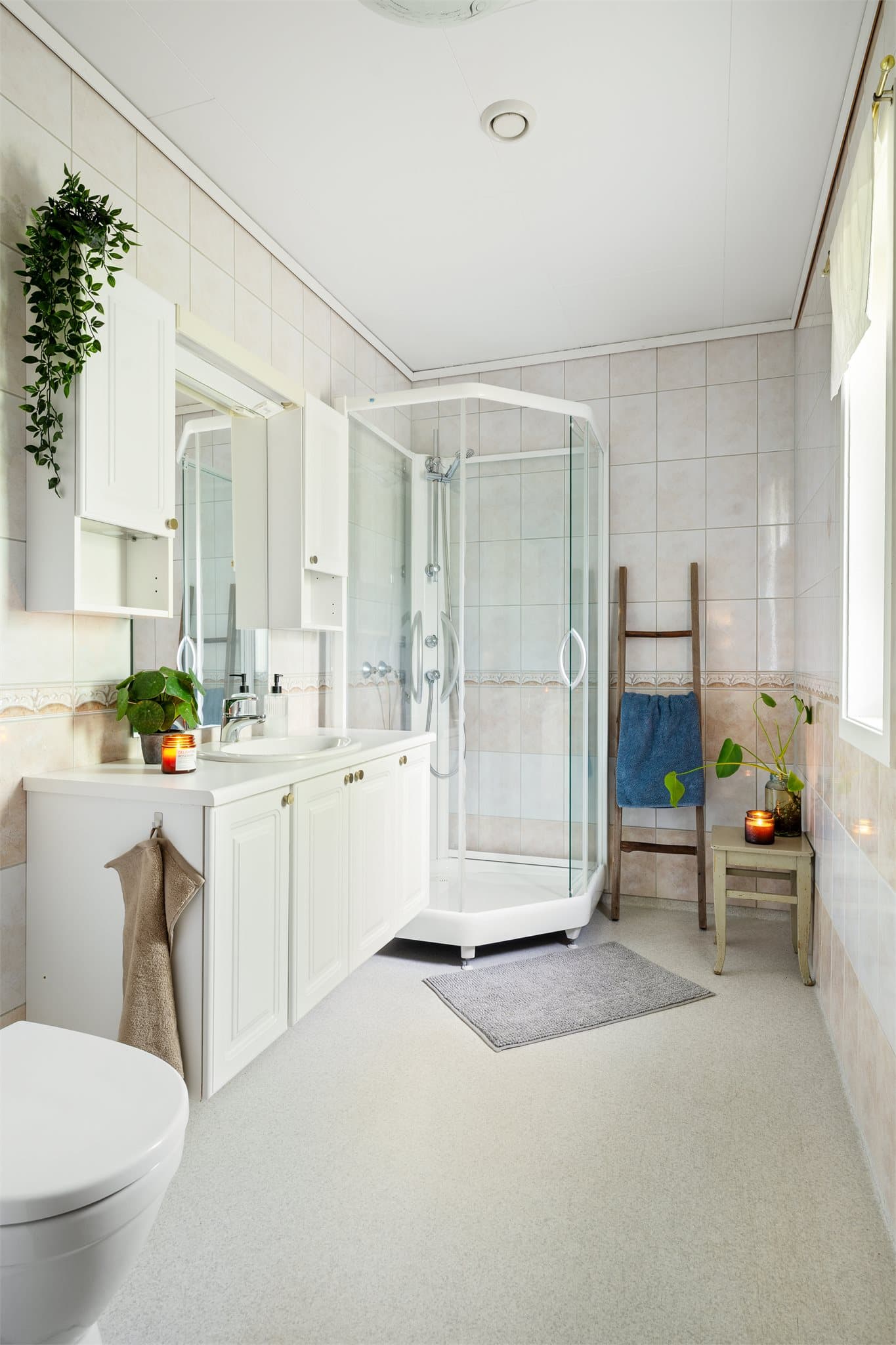 Badet har vinylbelegg på gulv med varme, flislagte vegger og en himling med tak-ess.