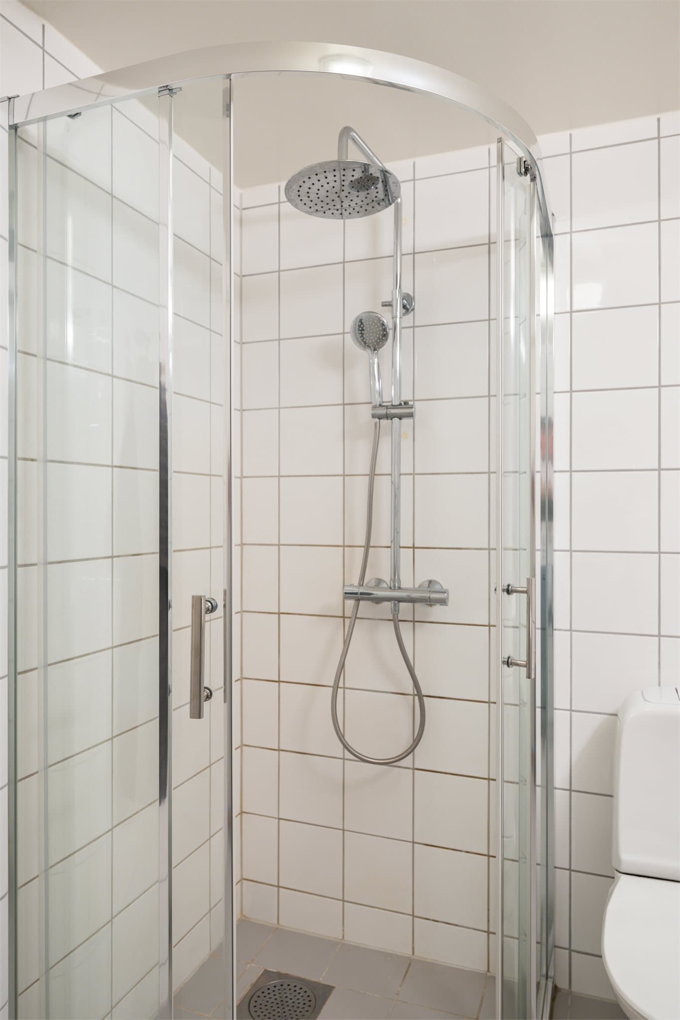 Romslig dusjhjørne med skyvedører, som er stilrent og praktisk.