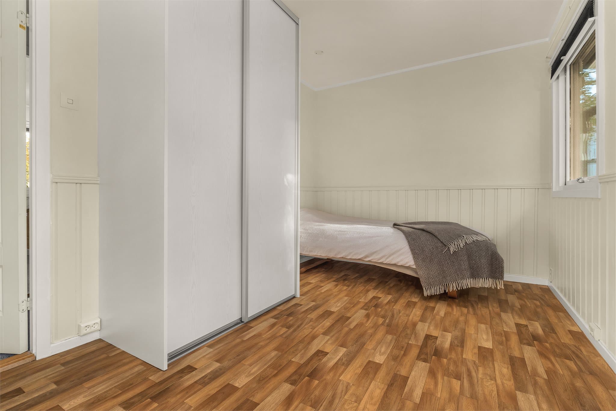 Soverom med panelte veggflater og plass til seng og garderobeskap.
