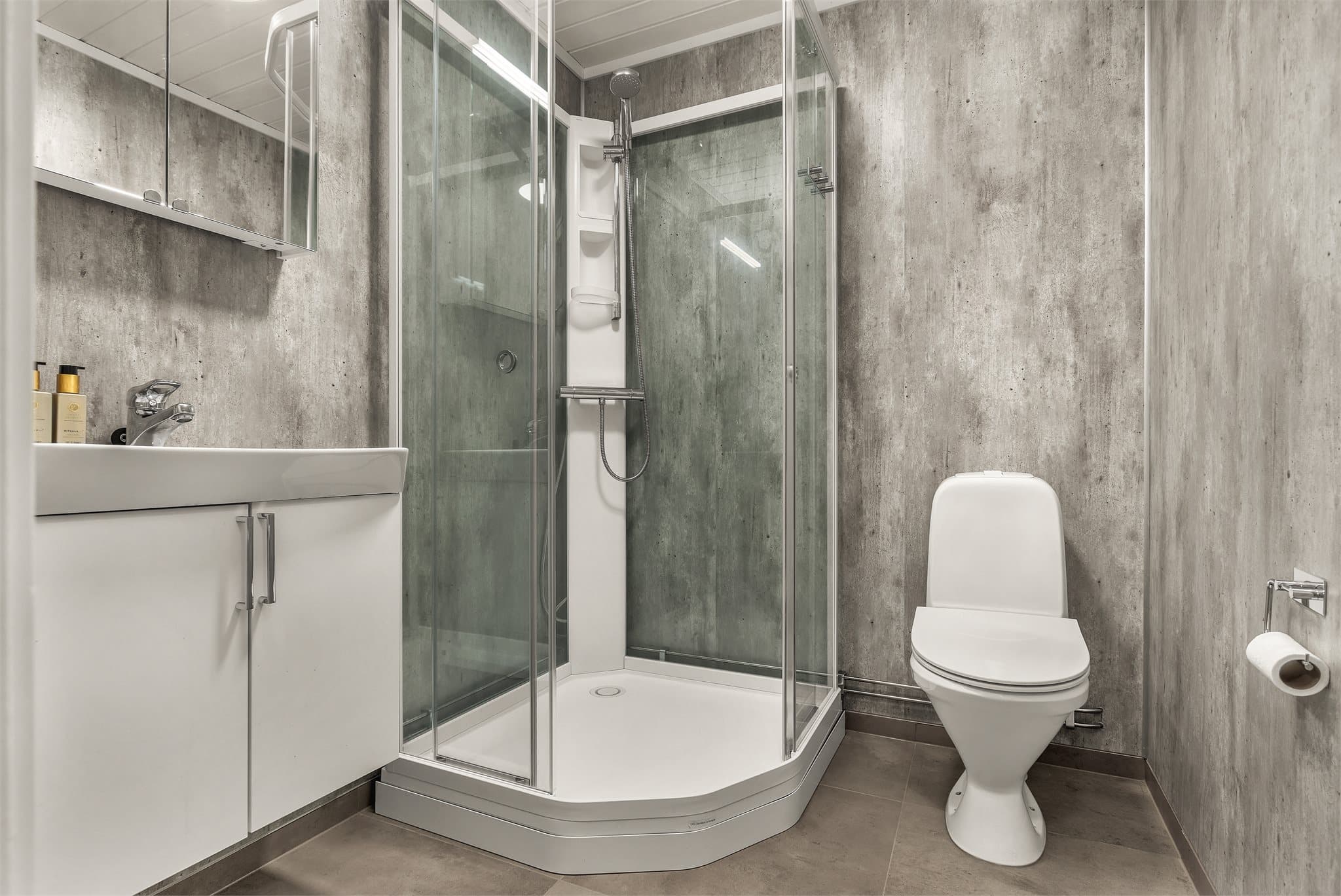 Badet i underetasjen har baderomsplater, flislagt gulv med varmekabler og dusjkabinett.