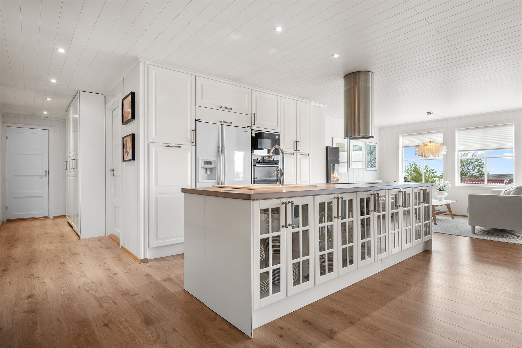 Kjøkkenet fremstår stilrent og moderne, med downlights i himlingen, integrerte hvitevarer og takhøye skap som gir gode oppbevaringsmuligheter.