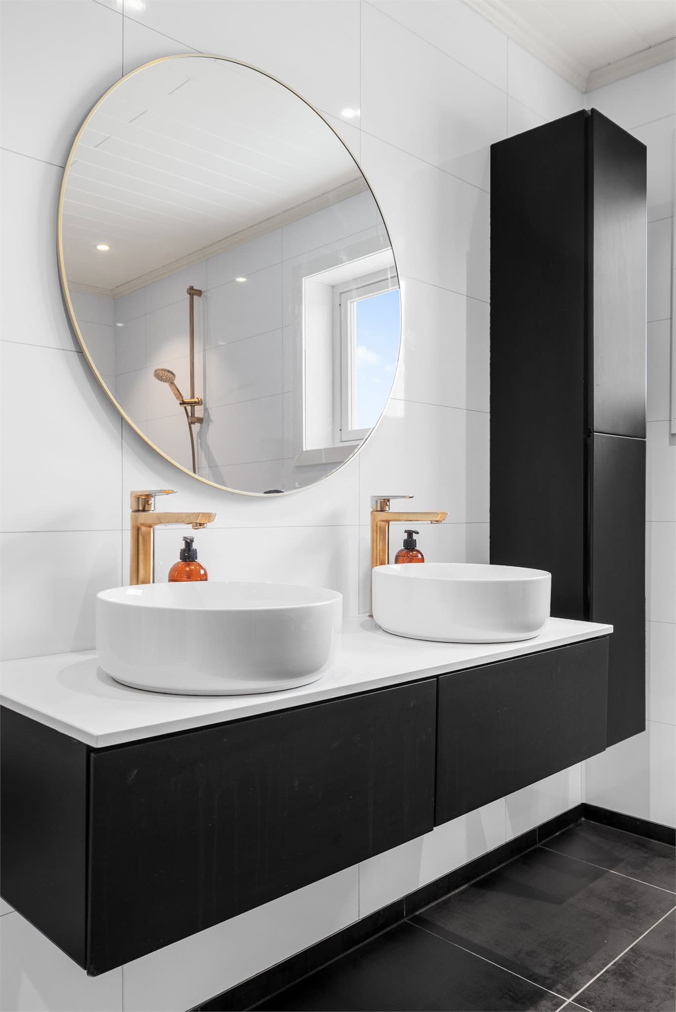 Gullfargede detaljer bidrar til en lun og eksklusiv atmosfære i det mørke badet.