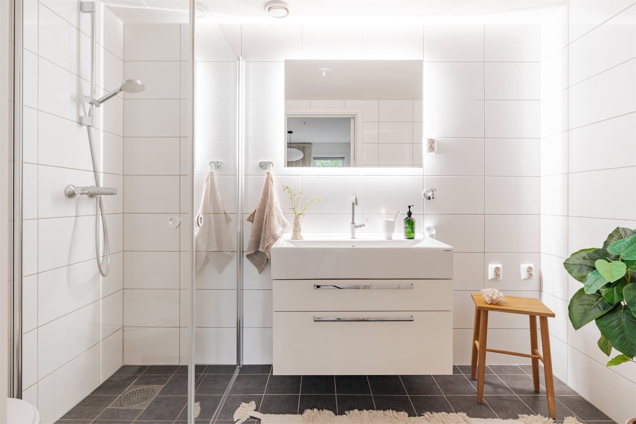 Det private badet er helfliset og utstyrt med dusjhjørne og vegghengt toalett.