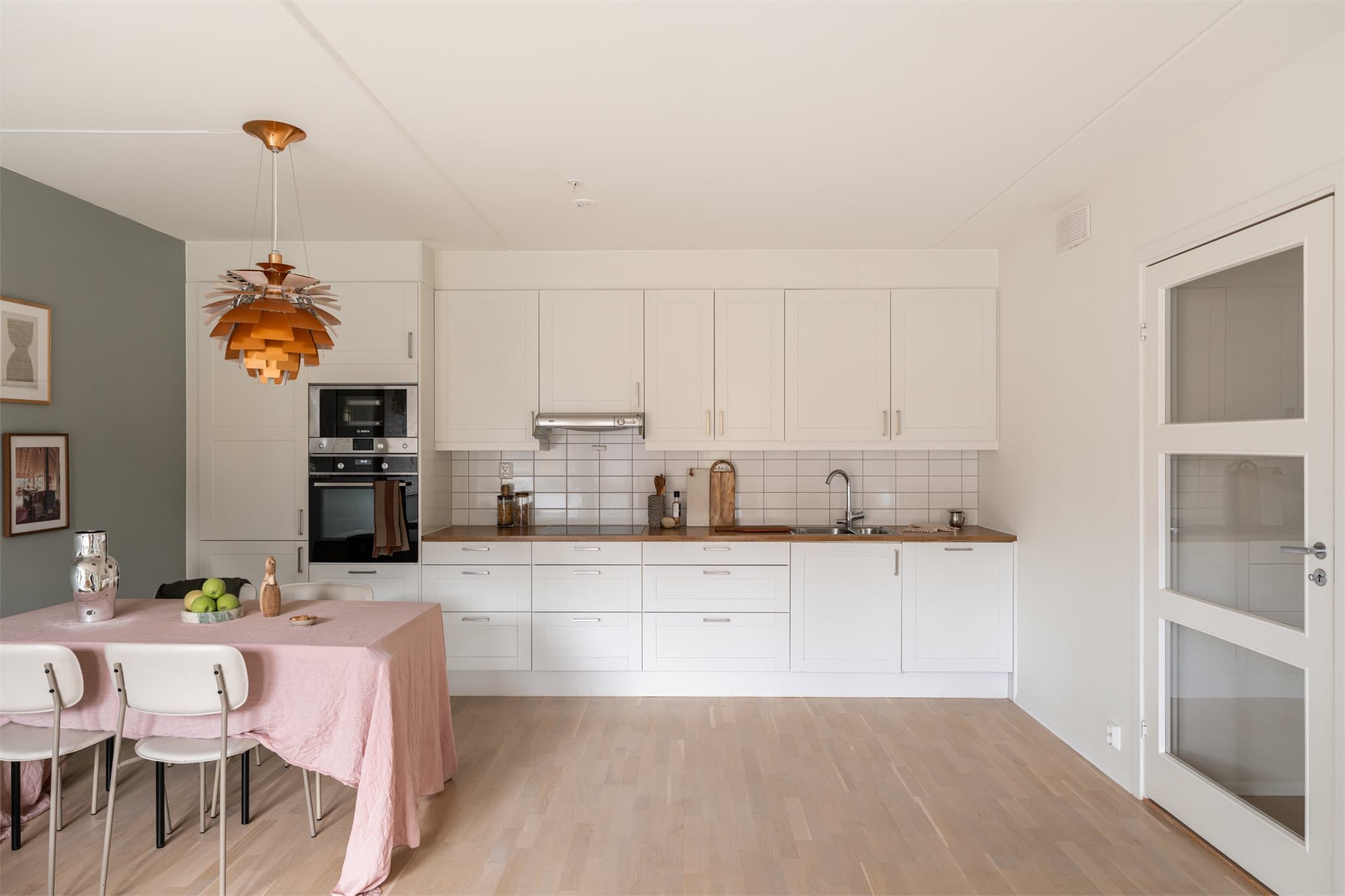 Moderne og innholdsrikt kjøkken med hvite fronter og integrerte hvitevarer.