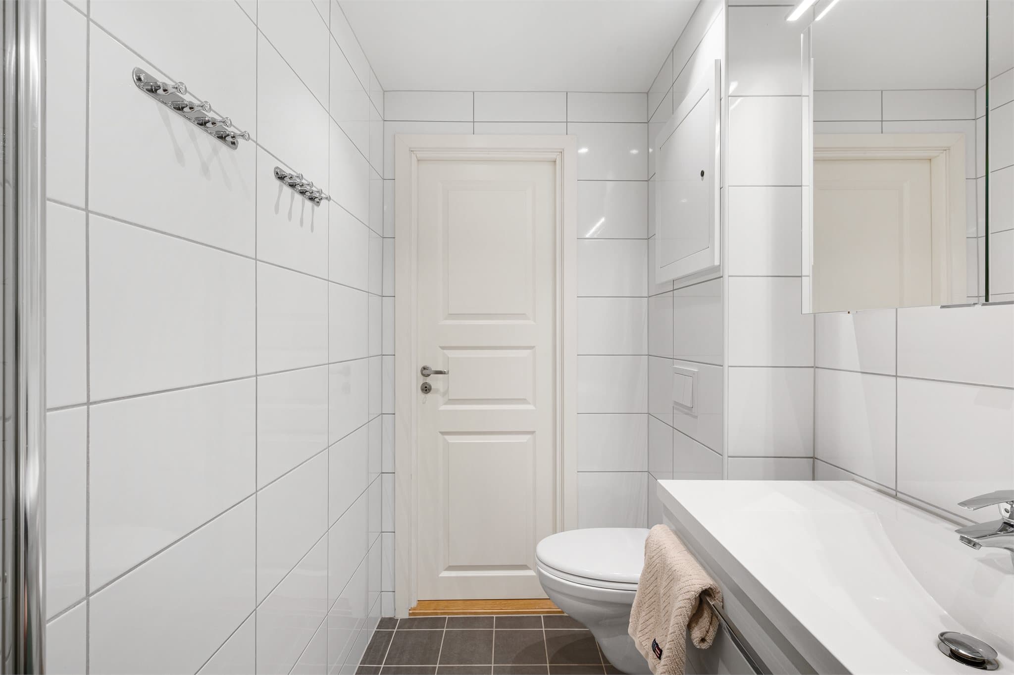 - Badet er innredet med heldekkende servant, vegghengt toalett, dusjhjørne, speilskap med belysning og opplegg for vaskemaskin -