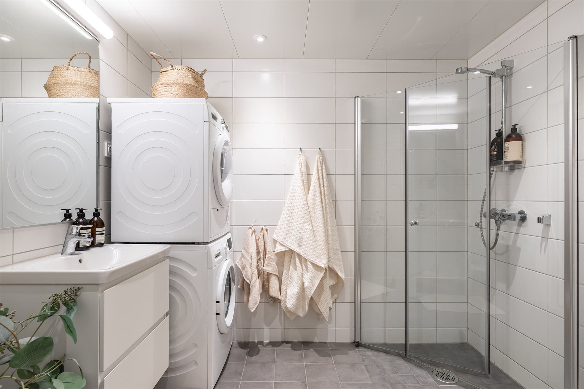 Badet fremstår stilrent og funksjonelt med flislagte overflater og vannbåren gulvvarme.