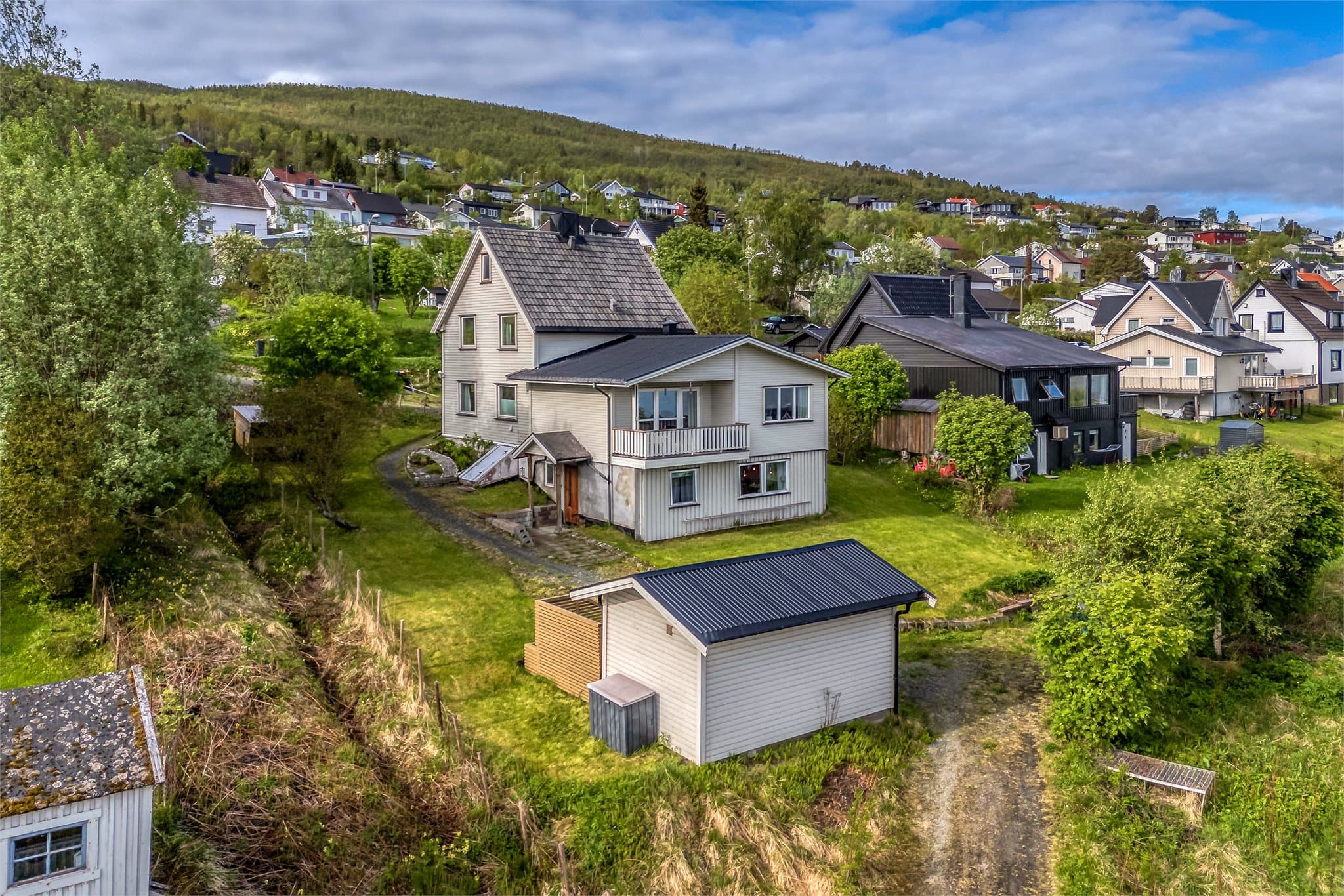 Eiendommen sett fra nedsiden, med utebod i forgrunnen.