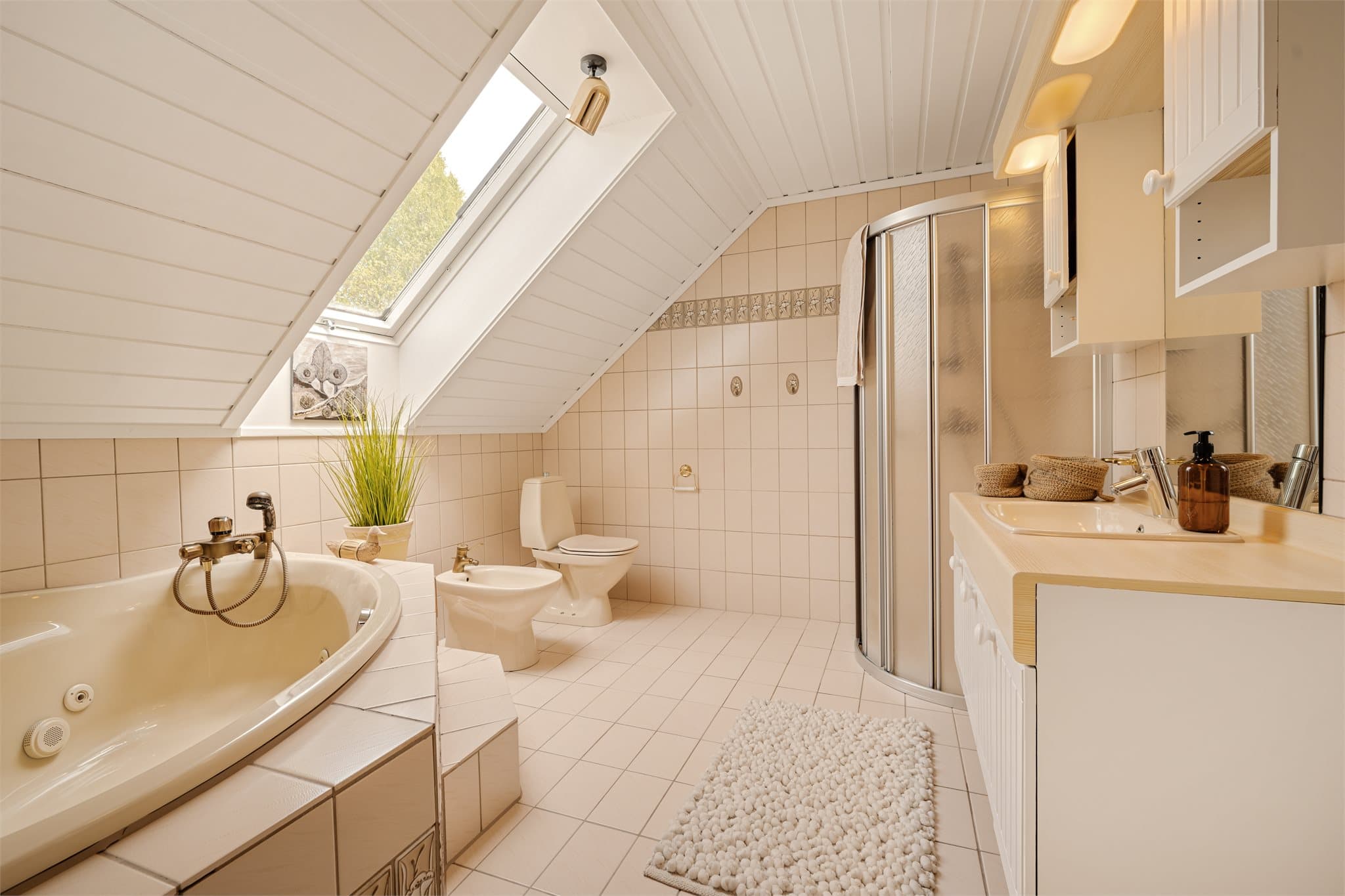 Badet er innredet med klosett, bidé, hjørnebadekar, dusj og nedfelt servant på underskap.