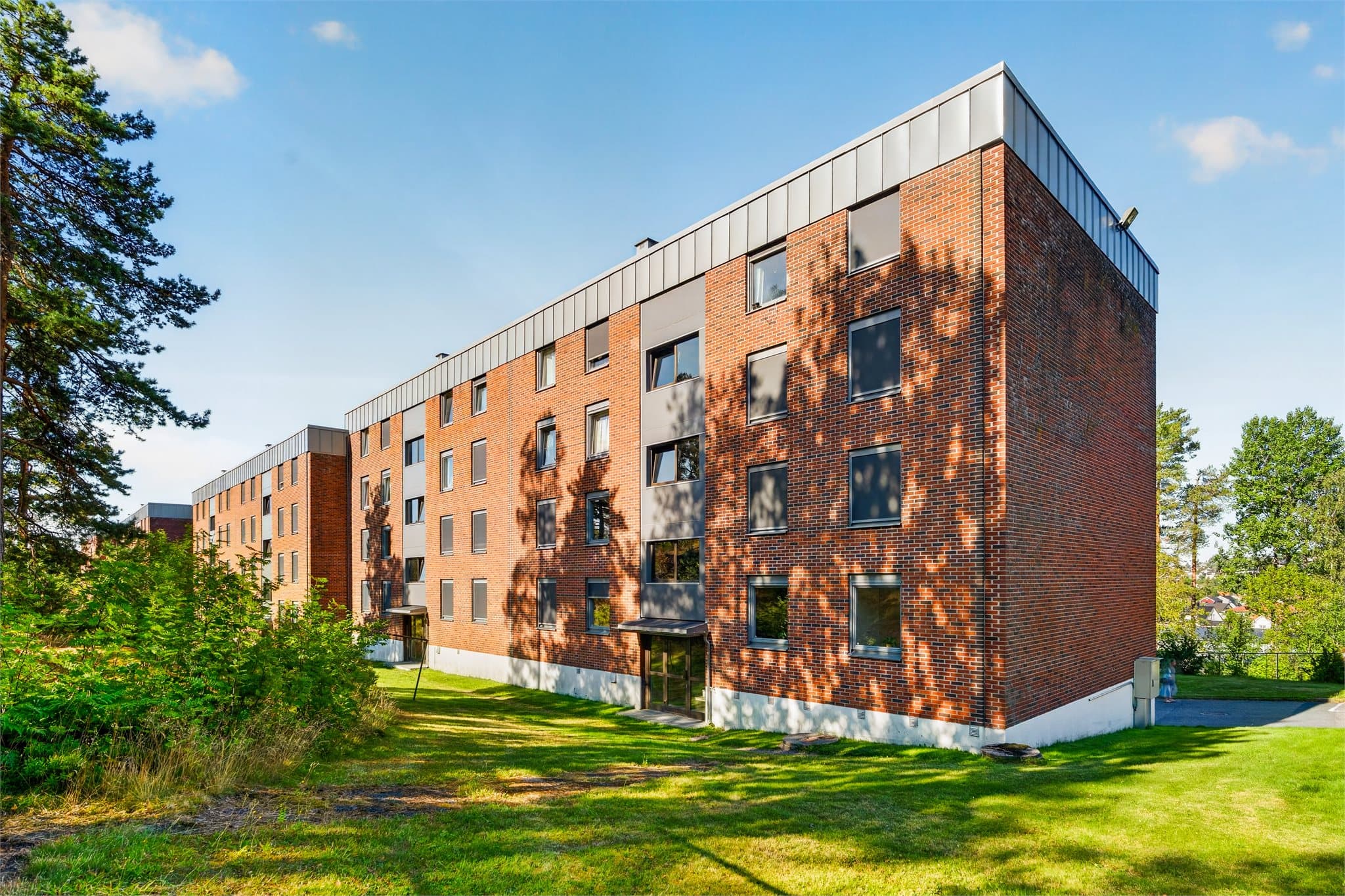 Fasade - det er et hyggelig område rundt boligblokken med grøntareal og skog.