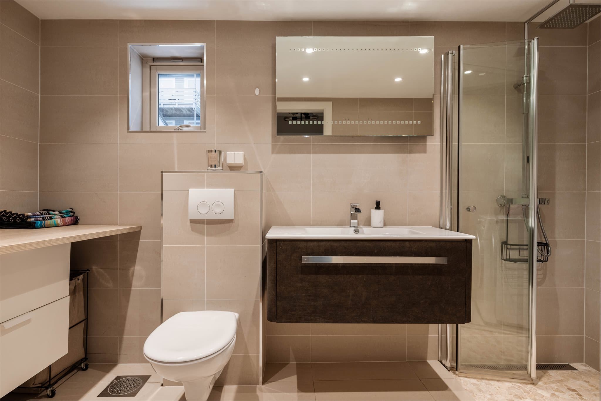 Flislagt bad fra 2015 med vegghengt toalett og dusjhjørne med innfellbare glassdører.