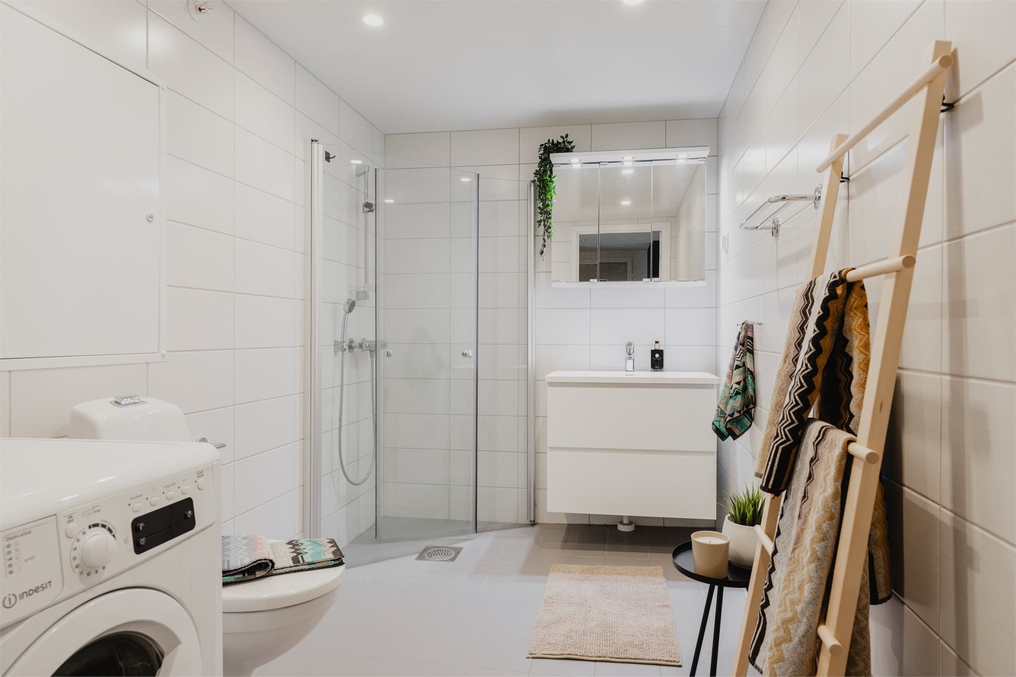 Badet er moderne og stilrent. Pent flislagte overfalter, vegghengt toalett, dusjhjørne og opplegg for vaskemaskin.