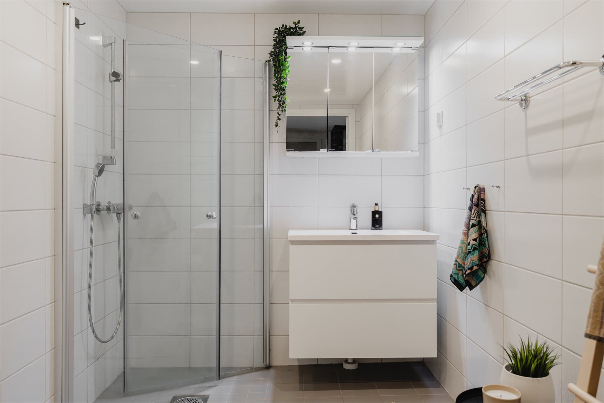 Badet har servant med skuffeseksjon og overskap med speilfronter og belysning.