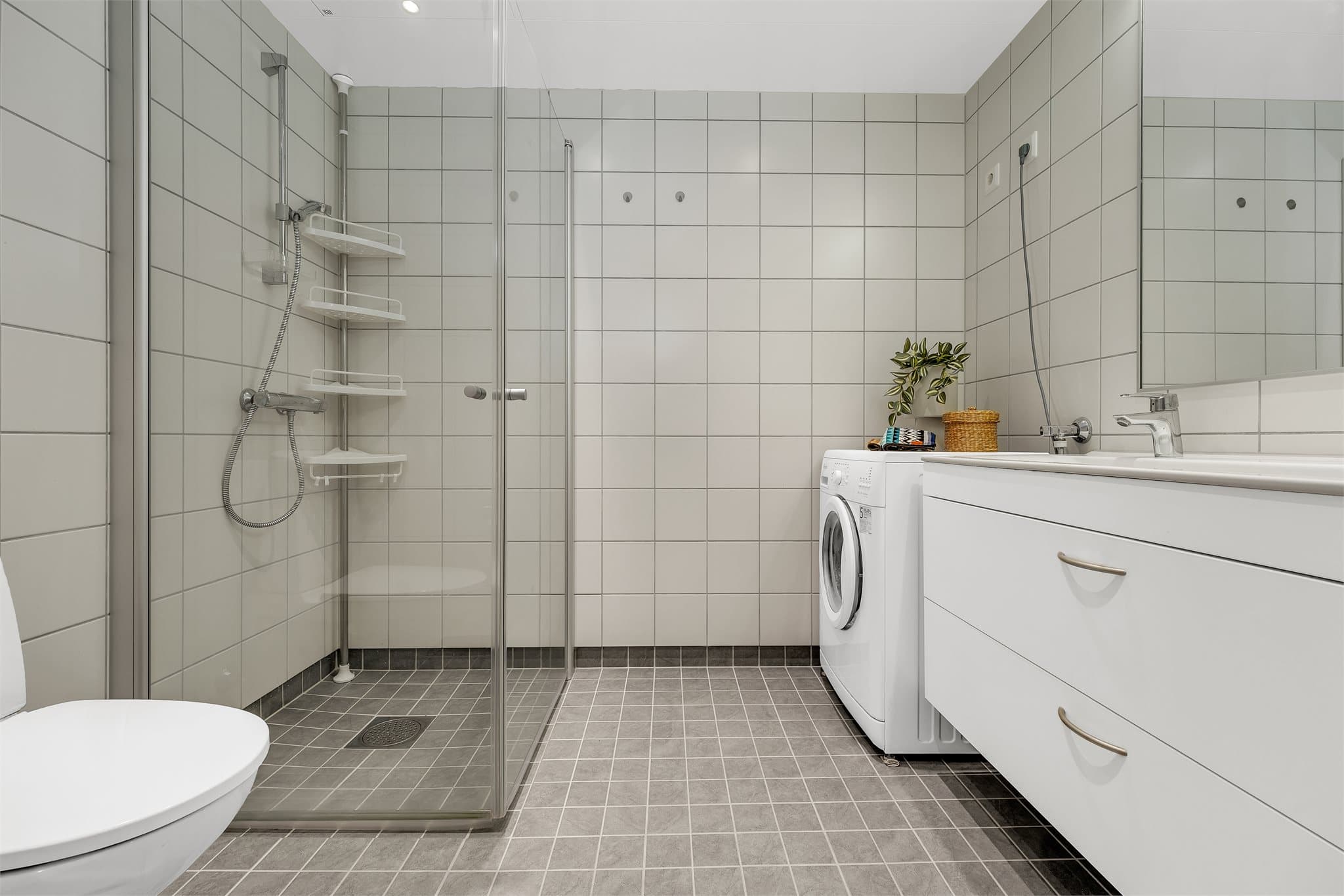 Flislagt bad med elektriske varmekabler i gulvet og opplegg for vaskemaskin.