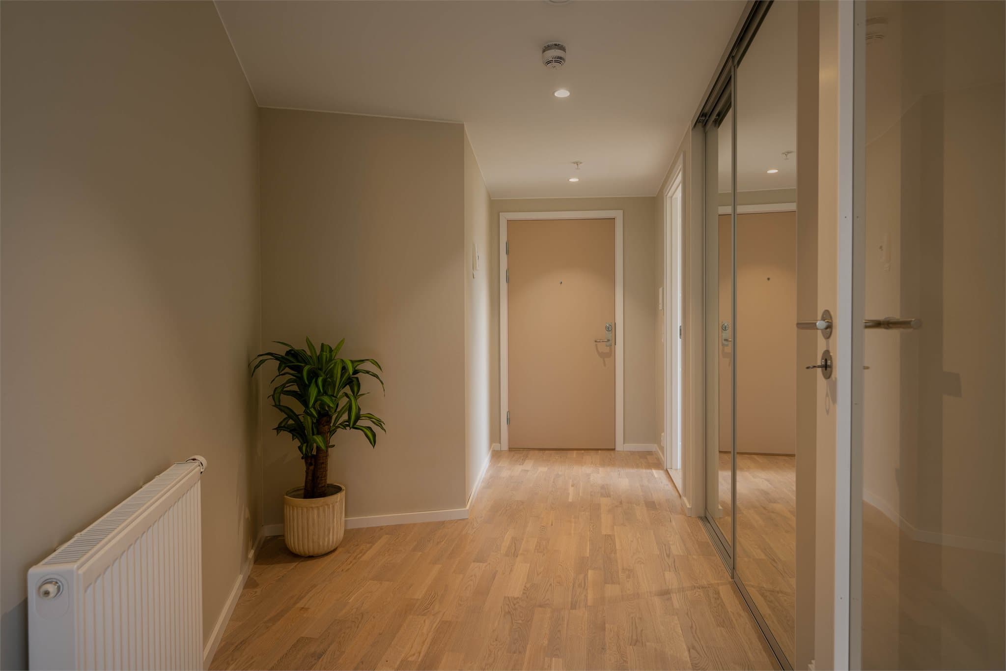 En romslig entré ønsker velkommen inn. Skyvedørsgarderobe med speilfronter gir rikelig med oppbevaringsplass for yttertøy og sko.