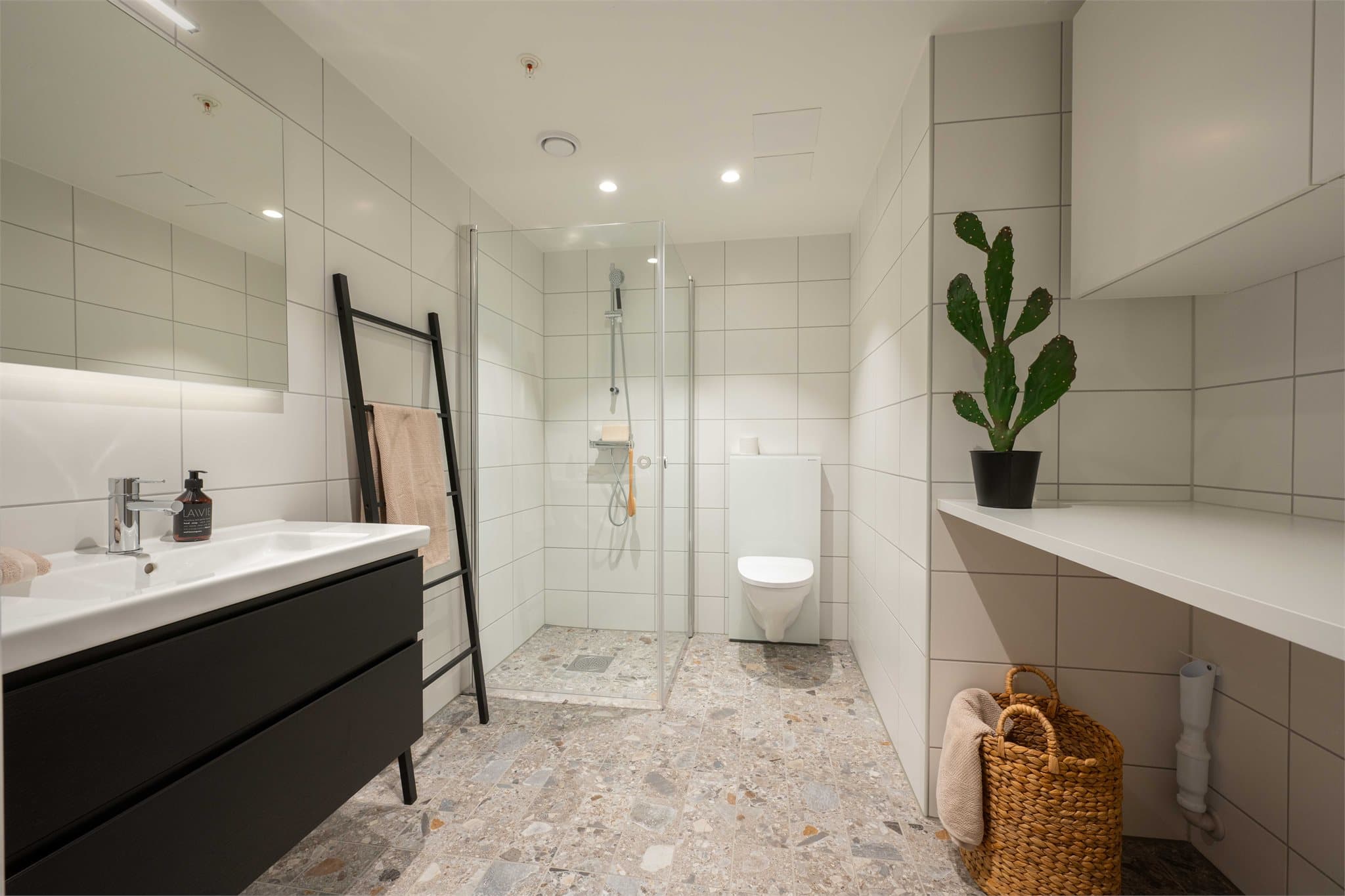 Hovedbadet har delikate gulv- og veggfliser, vegghengt toalett og opplegg for vaskemaskin.