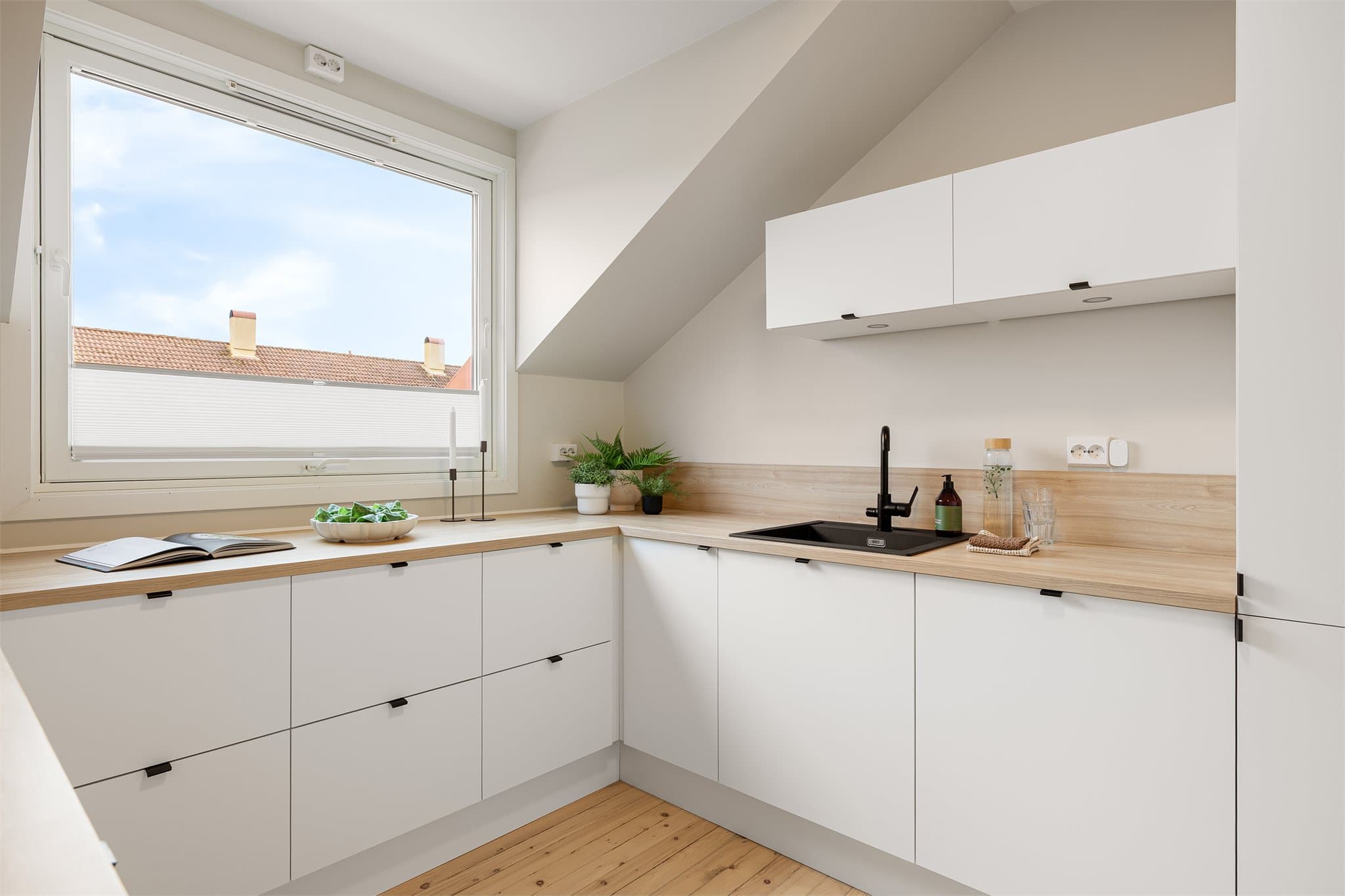 Kjøkkeninnredning med folierte fronter og laminert benkeplate under vinduet.