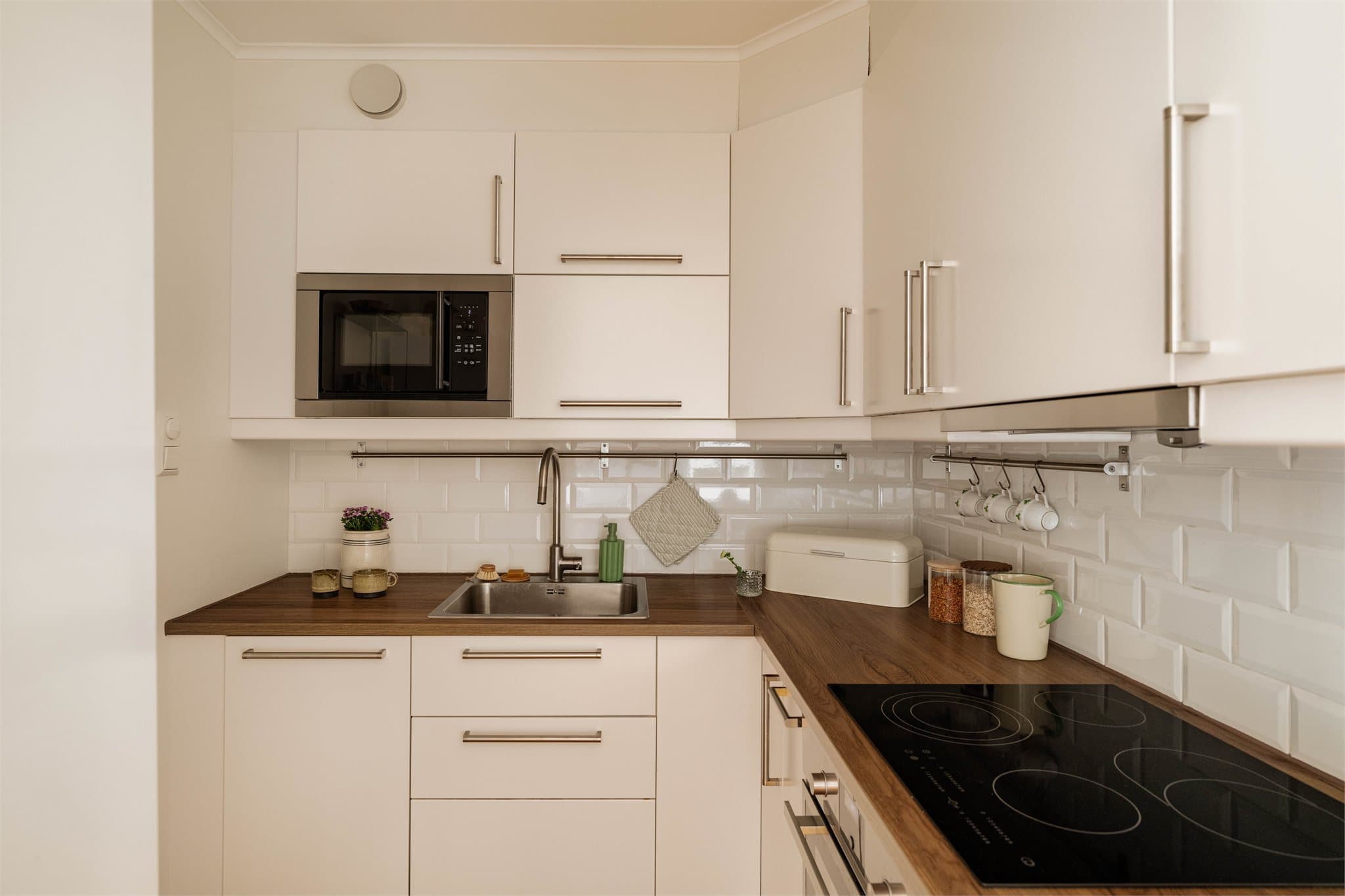 Kjøkkeninnredning fra IKEA, oppgradert i 2017, med glatte fabrikklakkerte fronter og laminat benkeplate med nedfelt kum i rustfritt stål, som gir et rent og funksjonelt uttrykk.