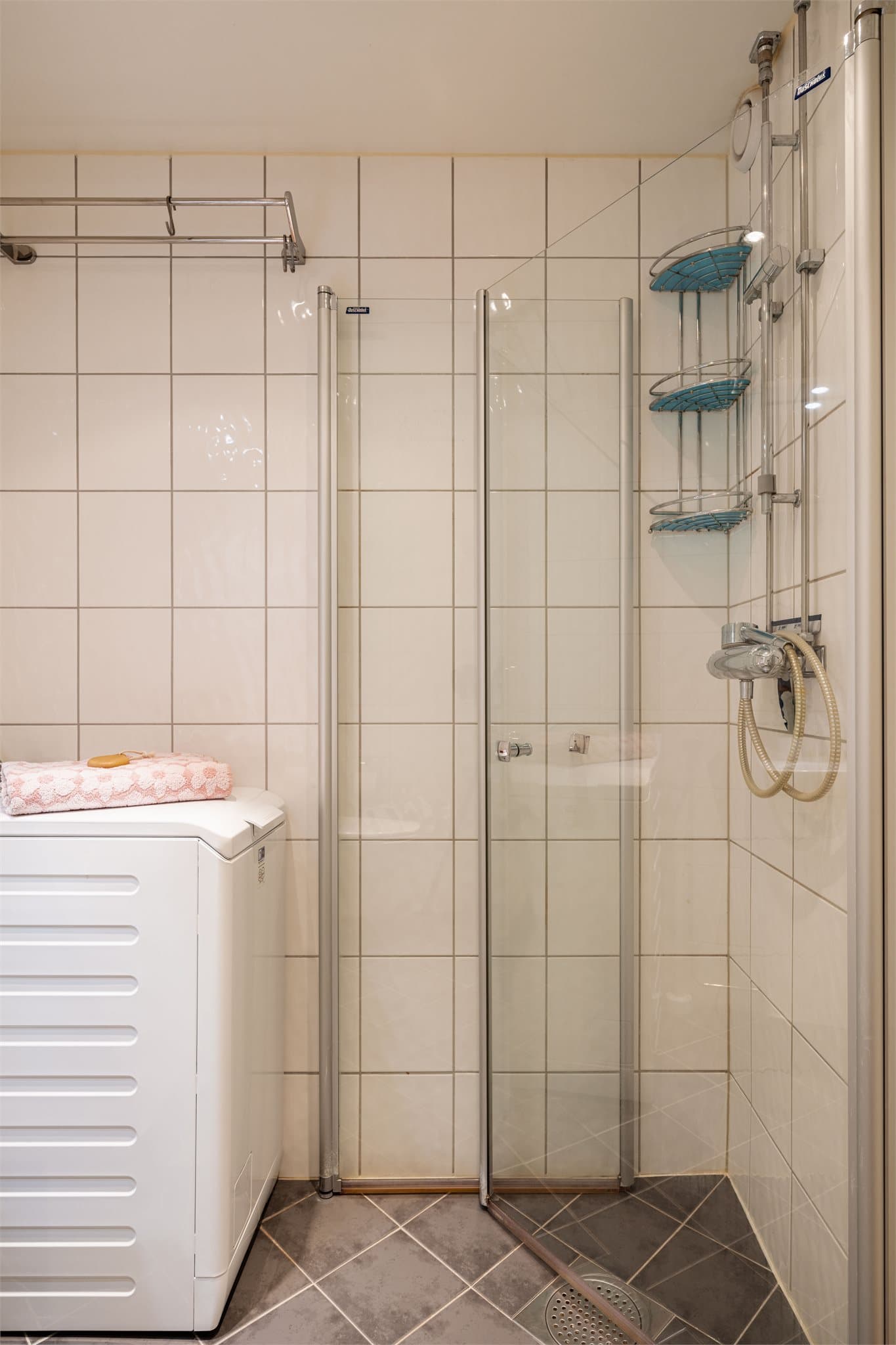 Dusjhjørne med svingdører, hånddusj og termostatstyrt blandebatteri. Praktisk opplegg for smal vaskemaskin.