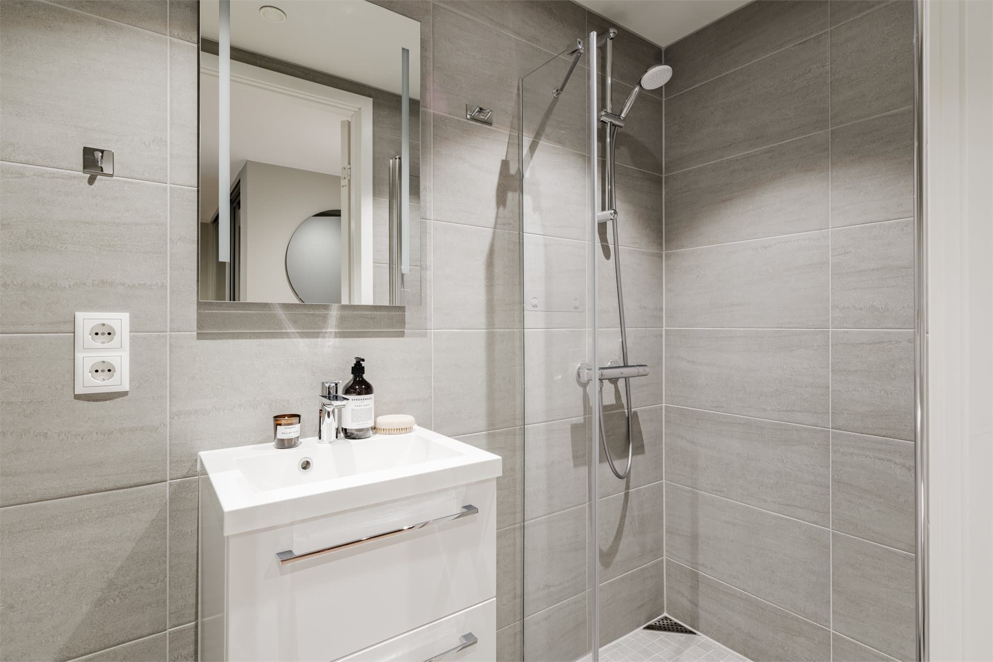 Det andre badet er stilfullt med behagelig gulvvarme og en dusjnisje bak innfellbare dører.