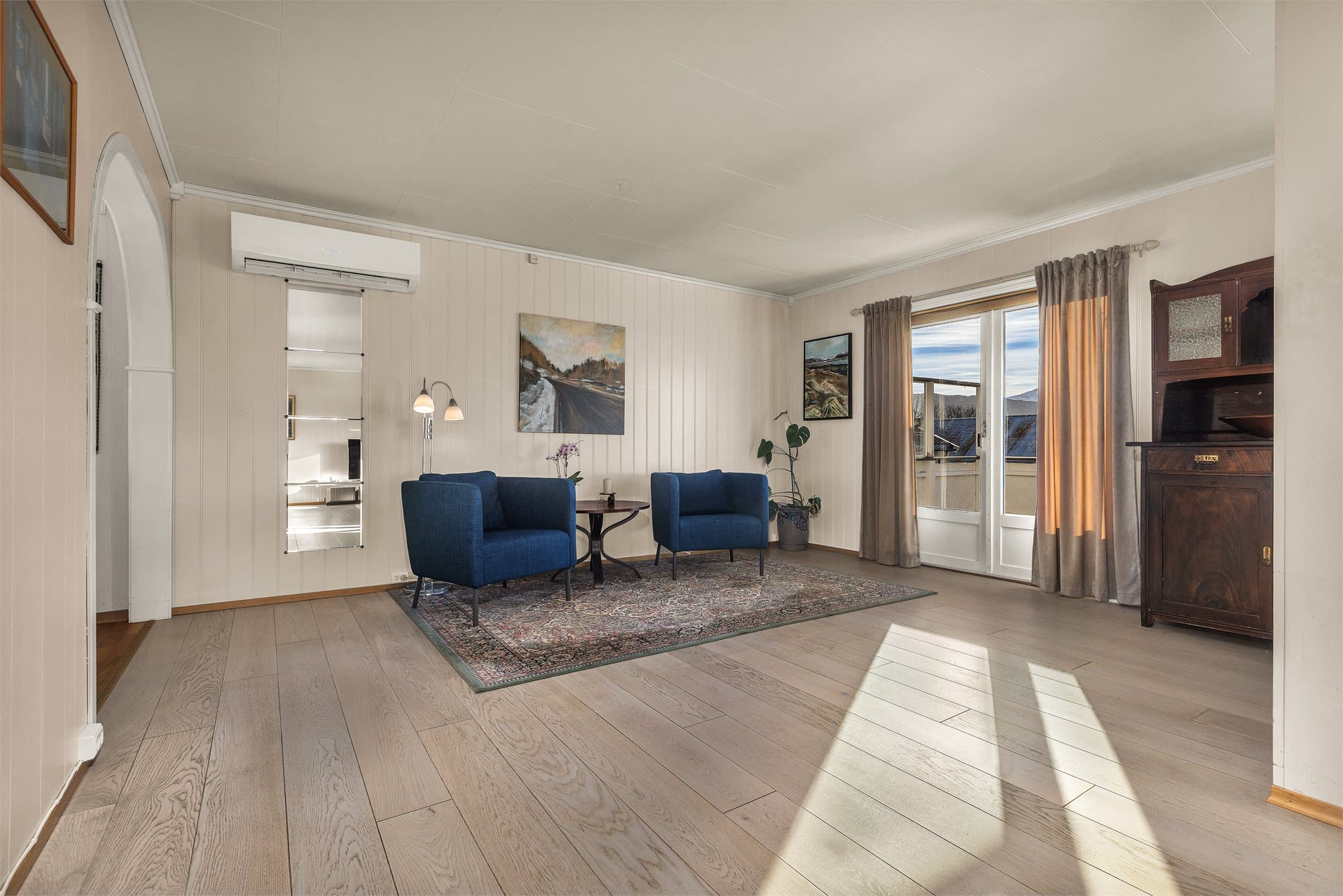 Tofløyet verandadør i tre slipper inn rikelig med dagslys og åpner ut mot hagen.