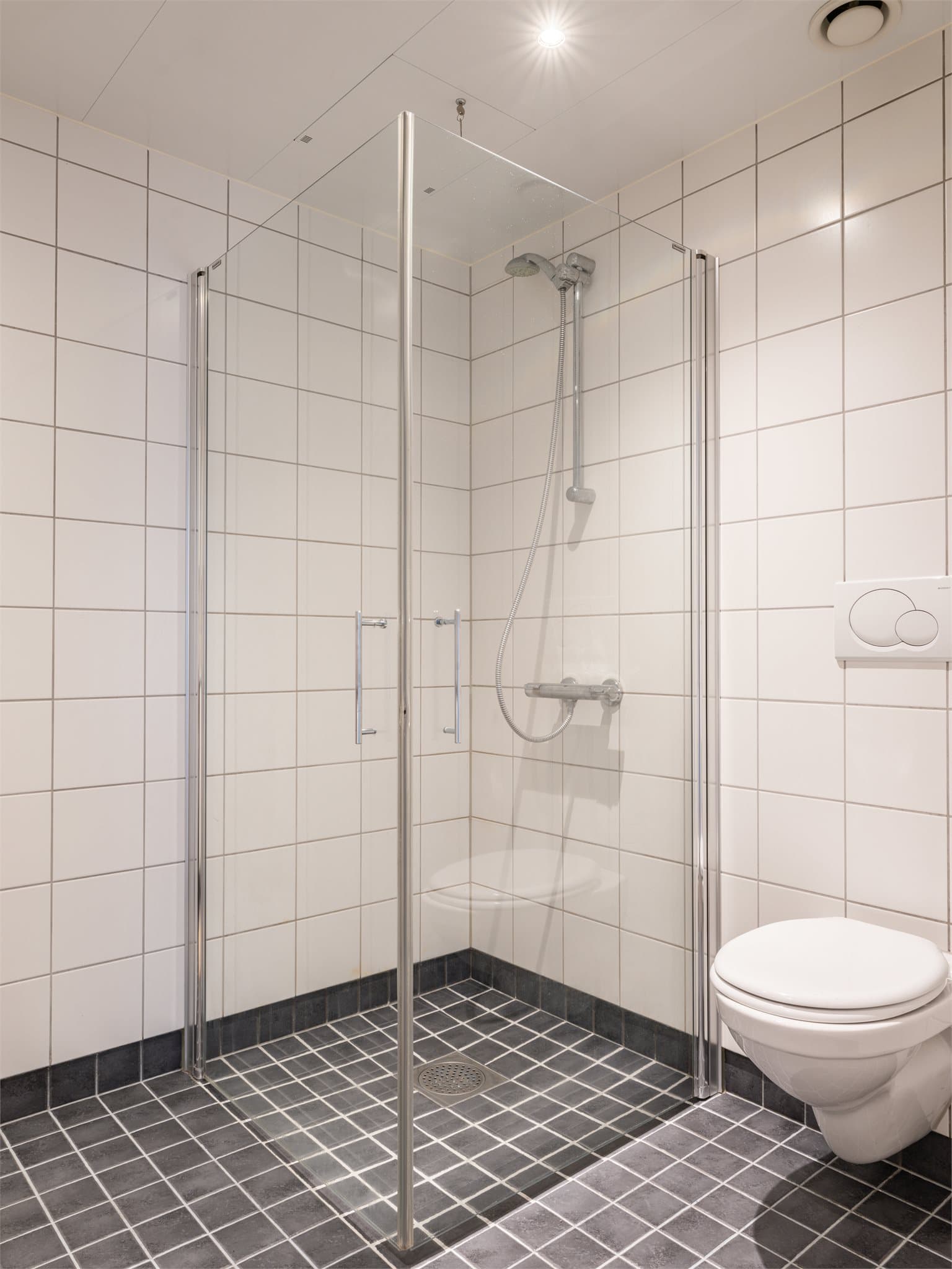 Dusjnisje bak dører i herdet glass, både praktisk og stilfullt.